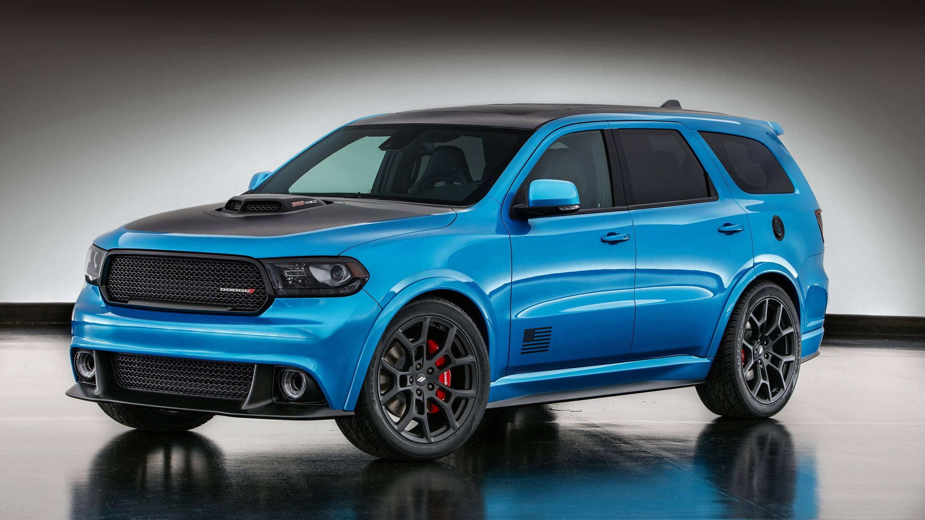 藍色杜蘭戈側視與反光鏡 壁紙 — 一輛充滿活力的藍色 Dodge Durango SRT，帶有黑色飾件和紅色制動卡鉗，在反光地板上的工作室燈光下閃閃發光。