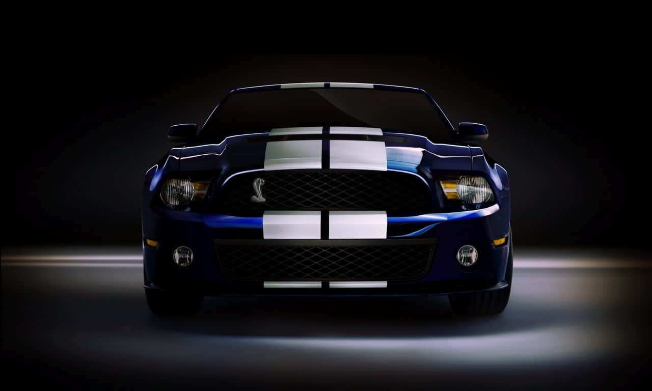 藍色 Shelby Mustang 帶有白色賽車條紋，在黑暗的工作室環境中照亮。