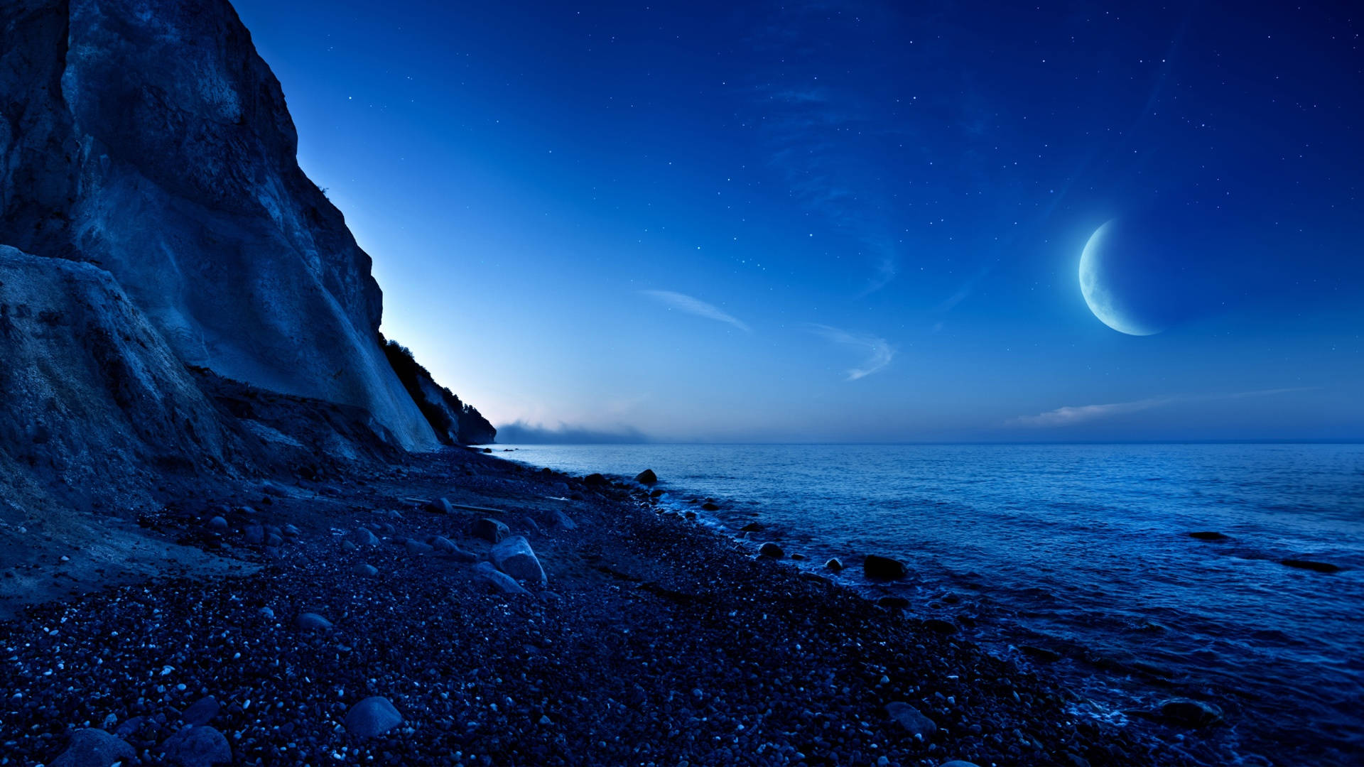 星空夜空下，岩石峭壁旁平靜海洋上的新月