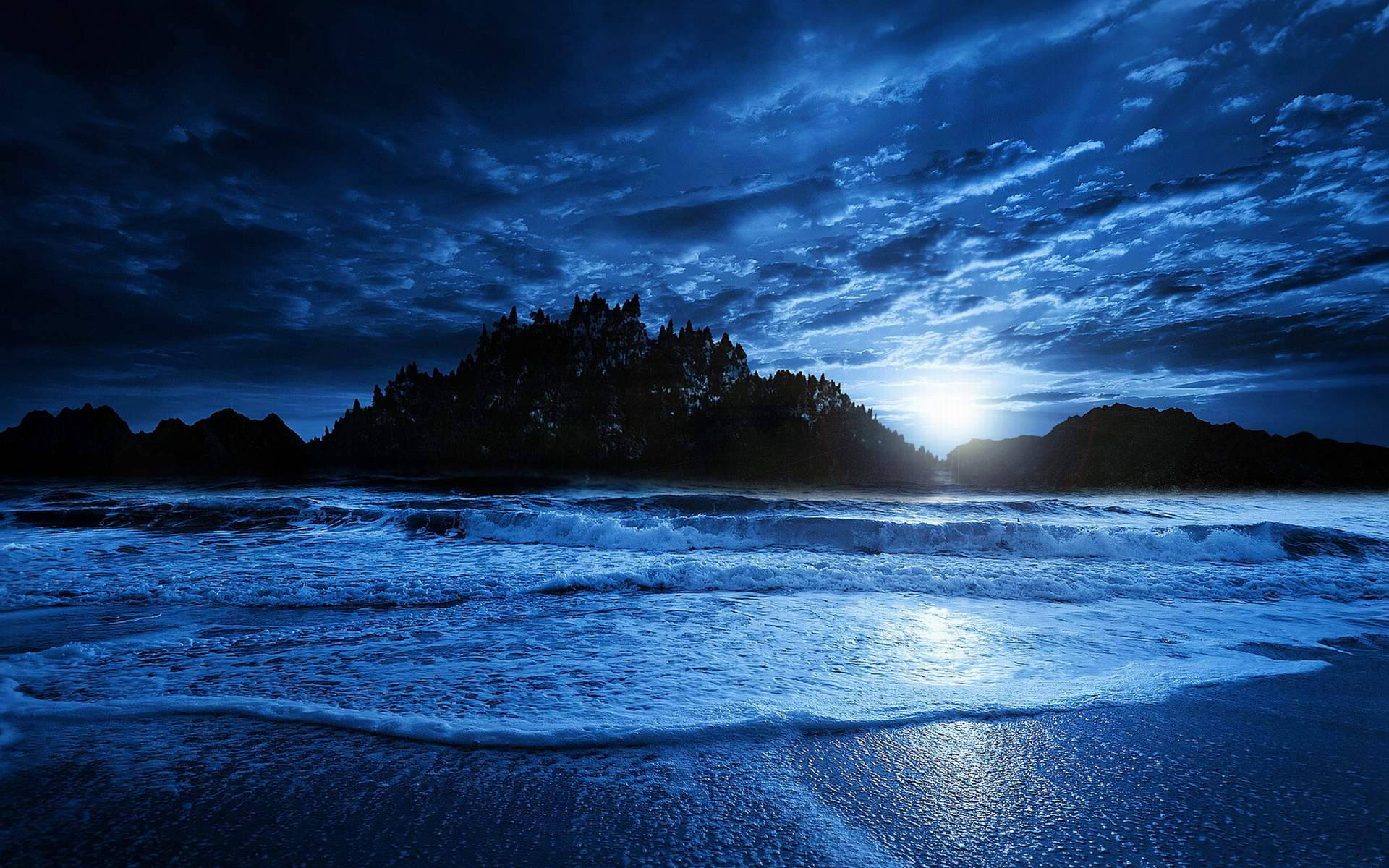 月光照亮的海浪在暴風雨的夜空下撞擊黑暗的岩石海岸。