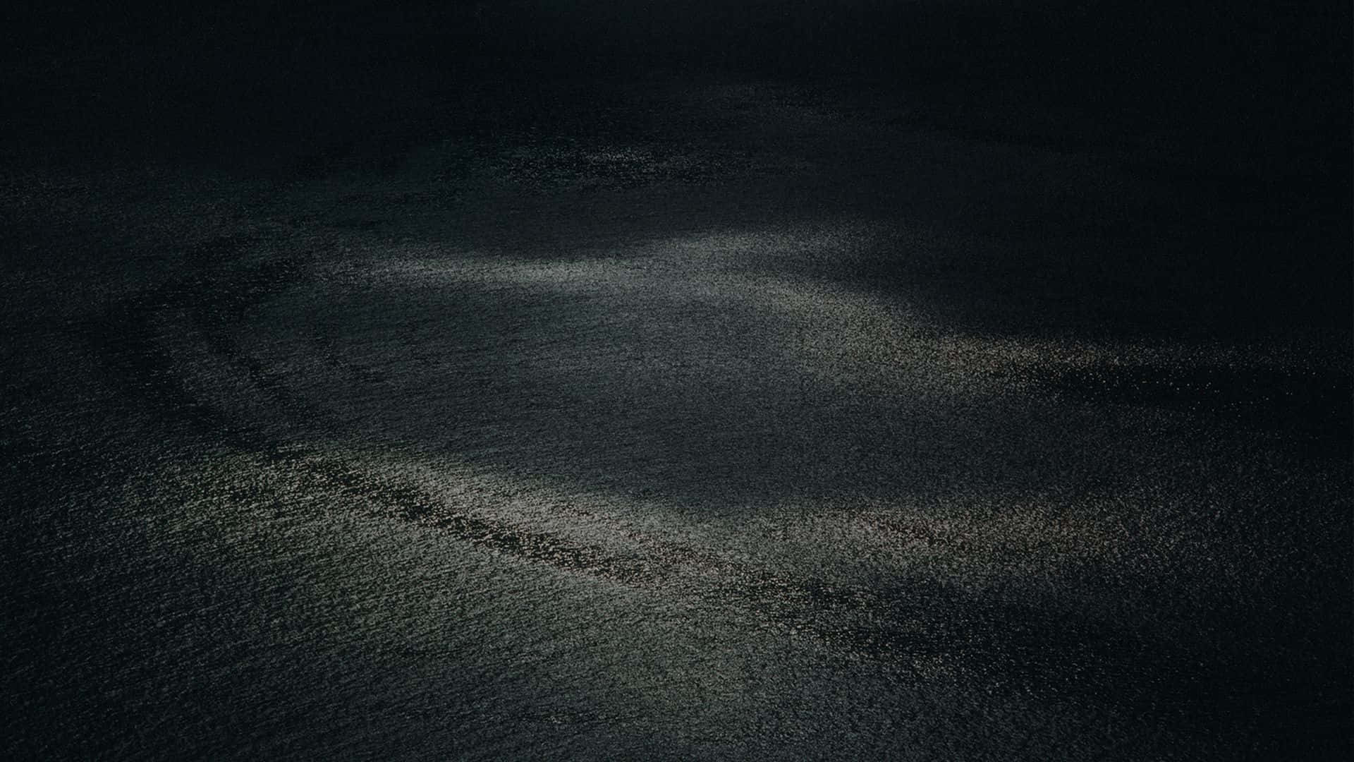夜間被聚光燈照亮的深色瀝青上的彎曲輪胎痕跡。