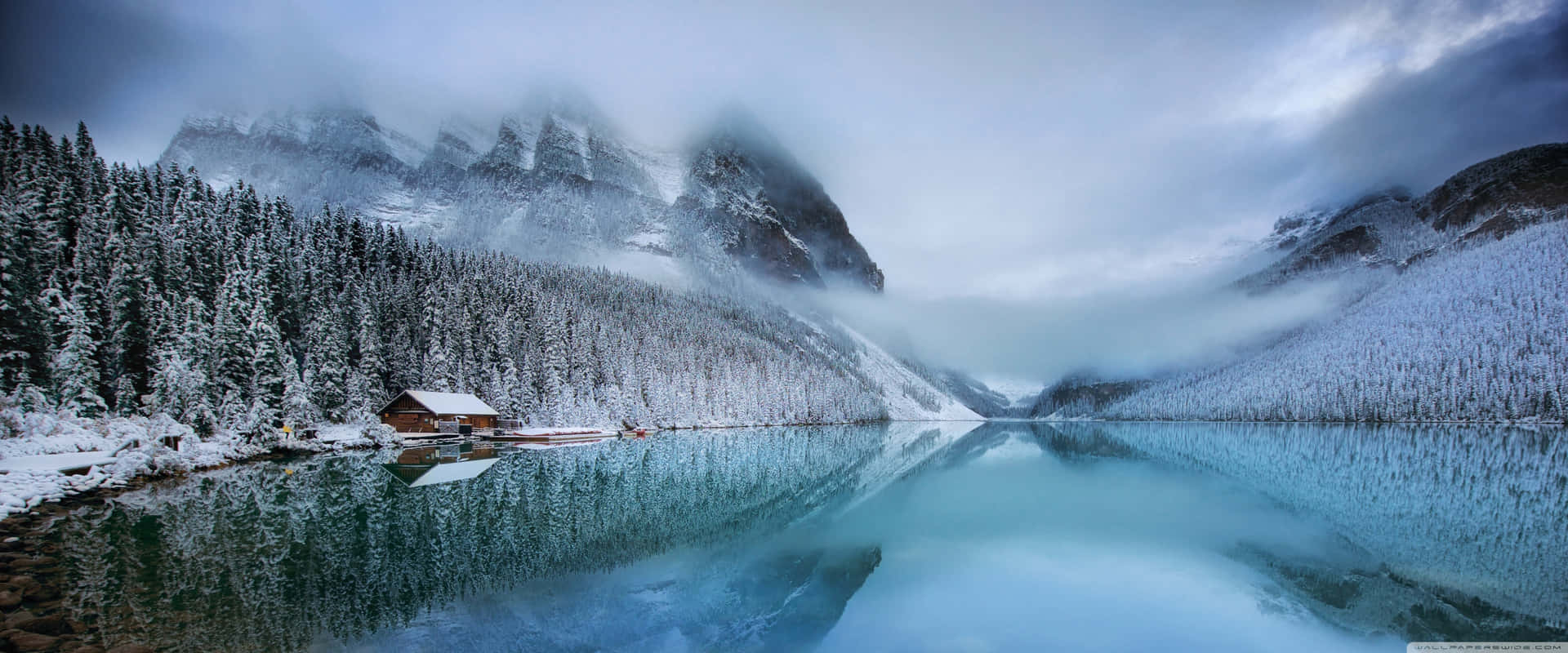 冰湖上的雪屋，背景有霧氣繚繞的山脈