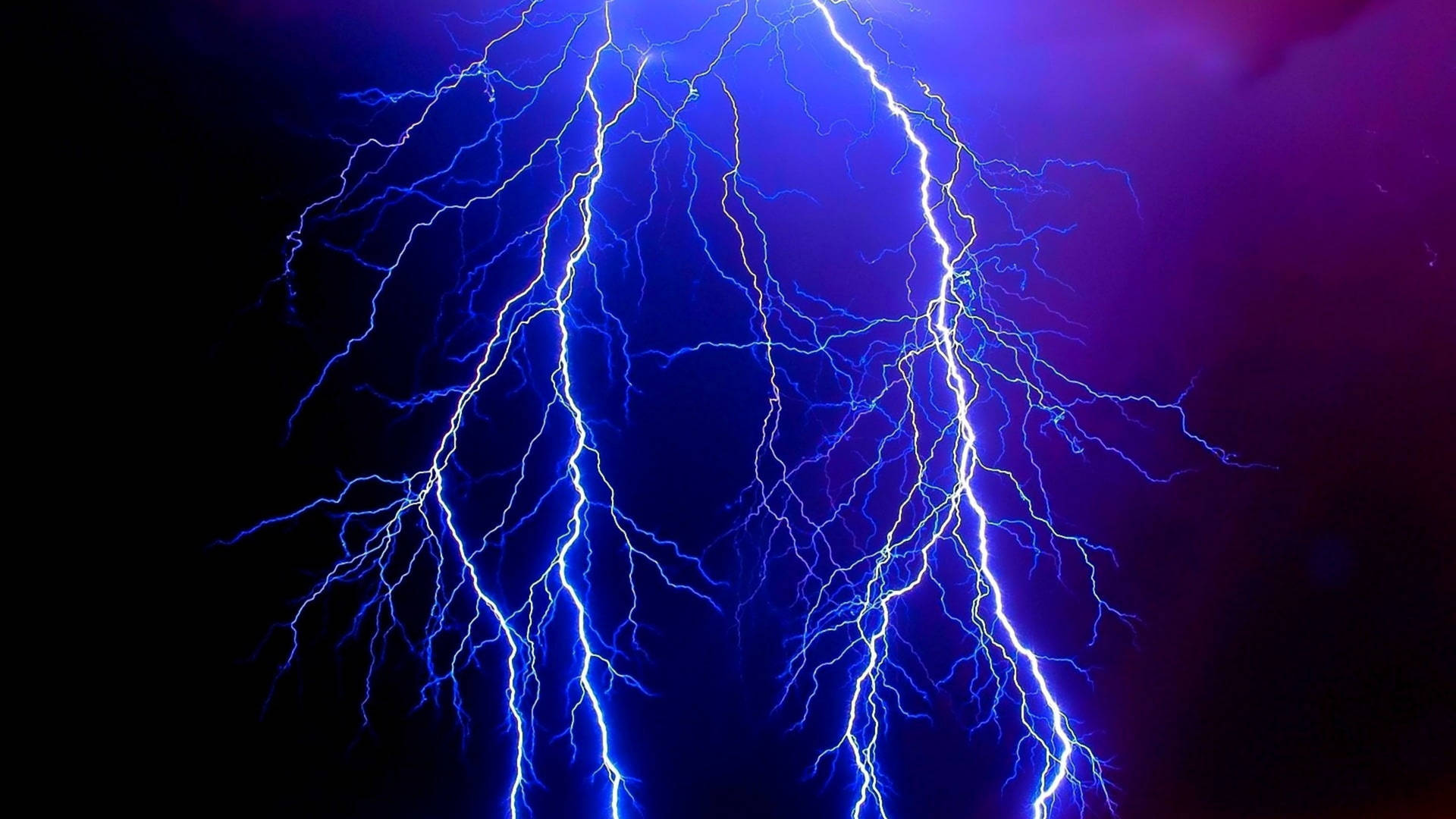 強烈的藍色閃電照亮了帶有紫色底色的黑暗暴風雨天空。