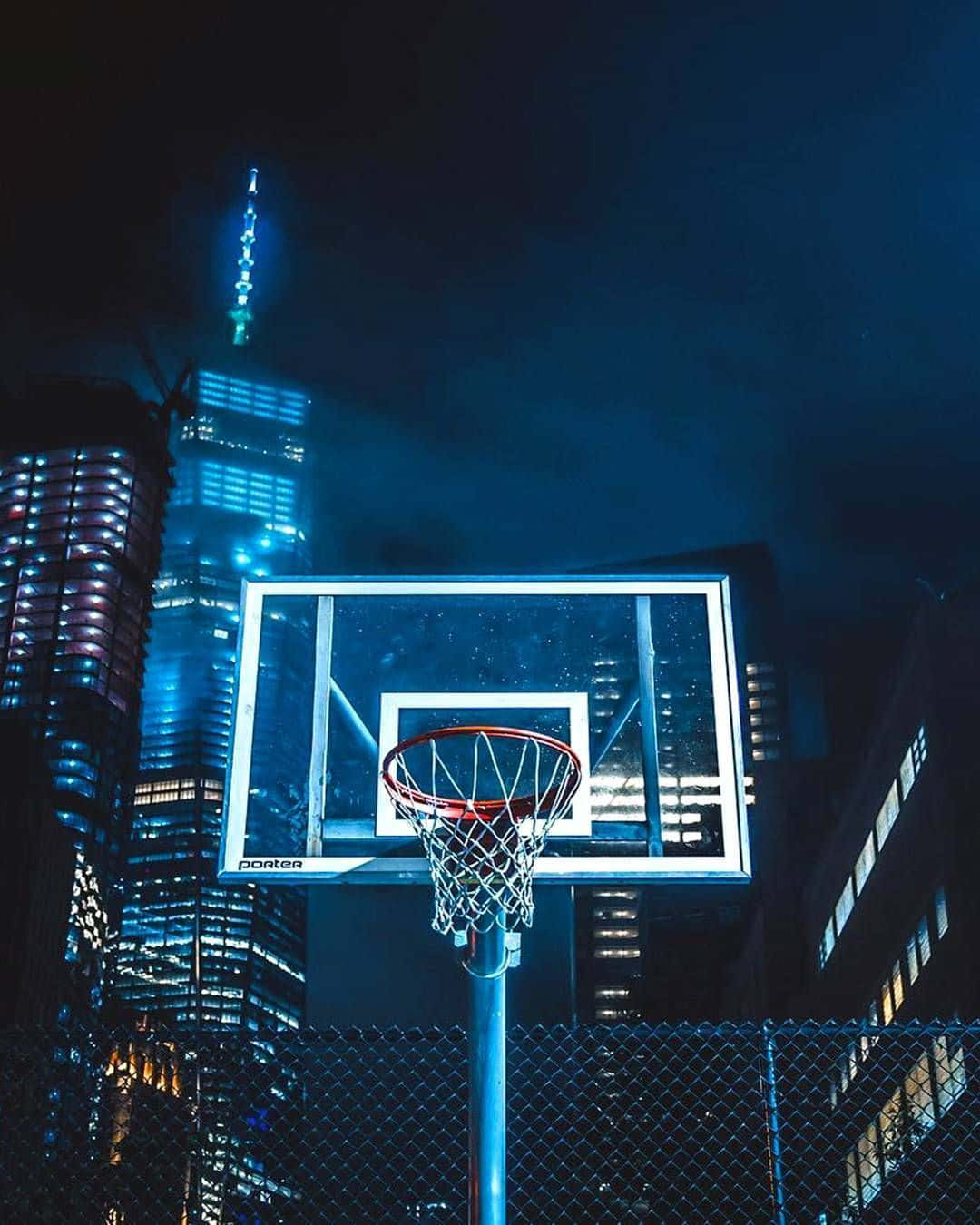 夜晚城市中的籃球框，後面有明亮的摩天大樓