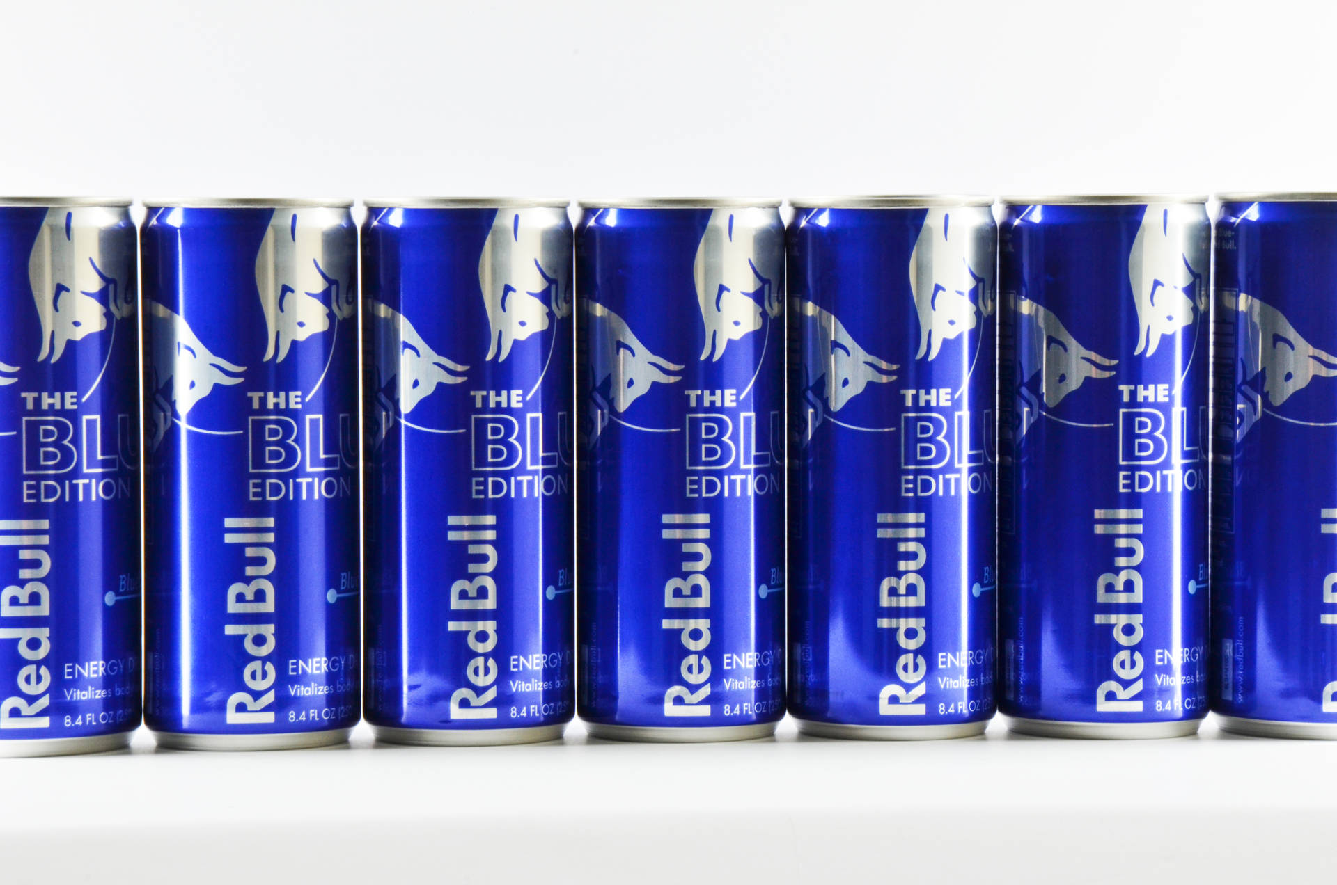 白色表面上的一排藍色Red Bull能量飲料罐。