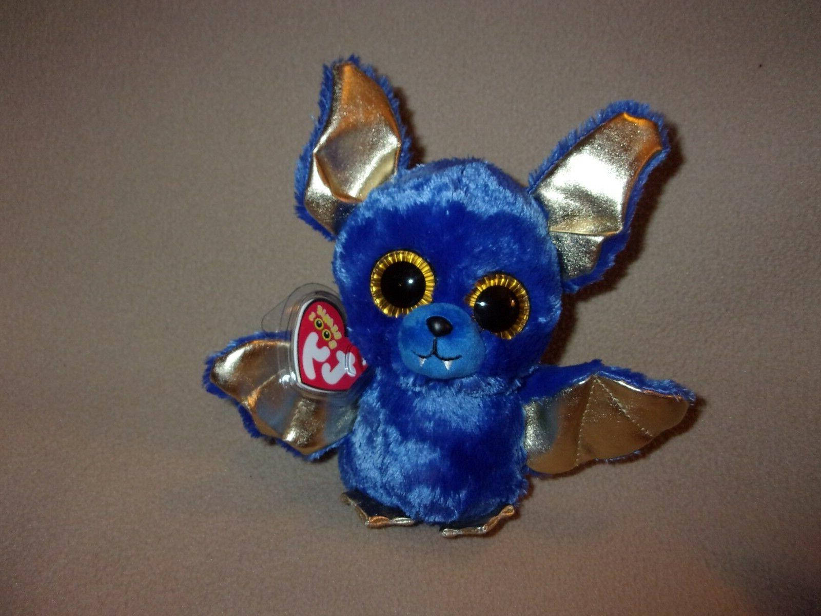 藍色蝙蝠 Beanie Boos 壁紙 — 一個柔軟的藍色蝙蝠玩具，帶有閃亮的金色翅膀和一雙黑色大眼睛，放在純灰色背景前。