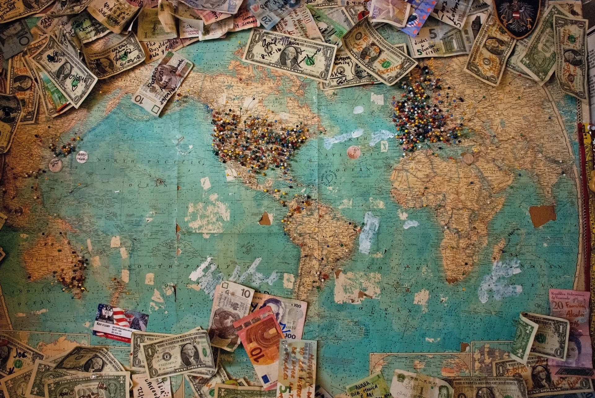 復古世界地圖，周圍環繞著國際貨幣和旅行圖釘。