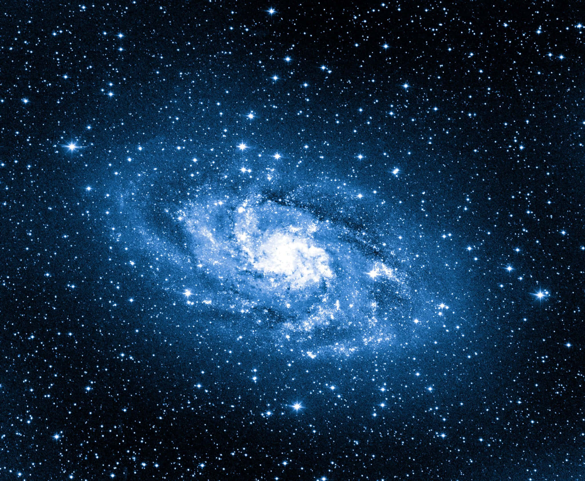 藍色銀河天文圖像 壁紙 — 一個令人驚嘆的螺旋星系，在深邃太空的星場中散發出藍色和白色的光芒。