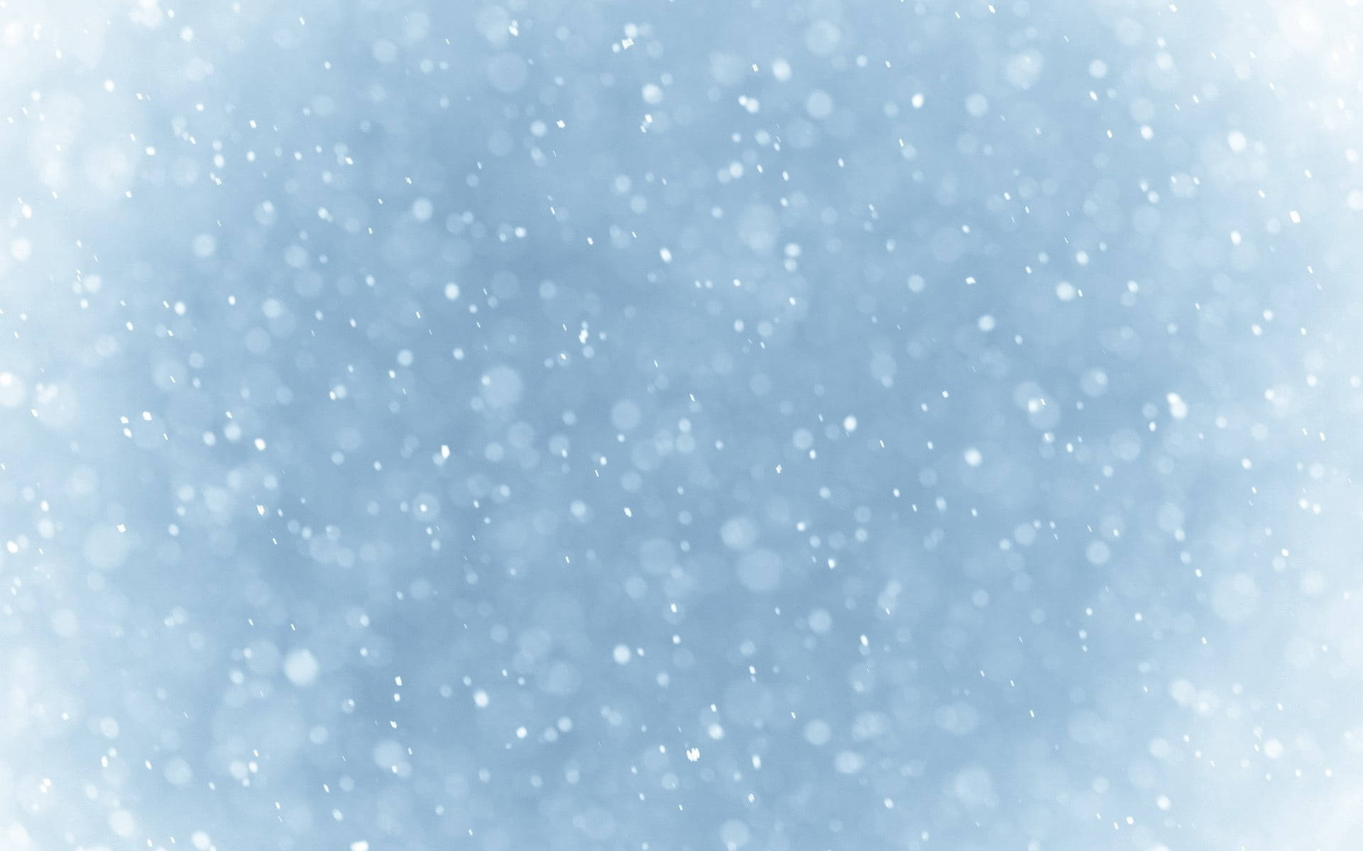 雪花在柔和的藍色冬日天空中輕輕飄落。