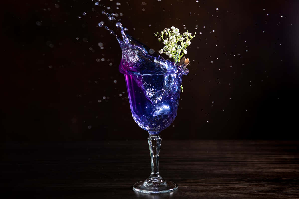 紫色飲料從帶有白花的玻璃杯中濺到深色木頭上。