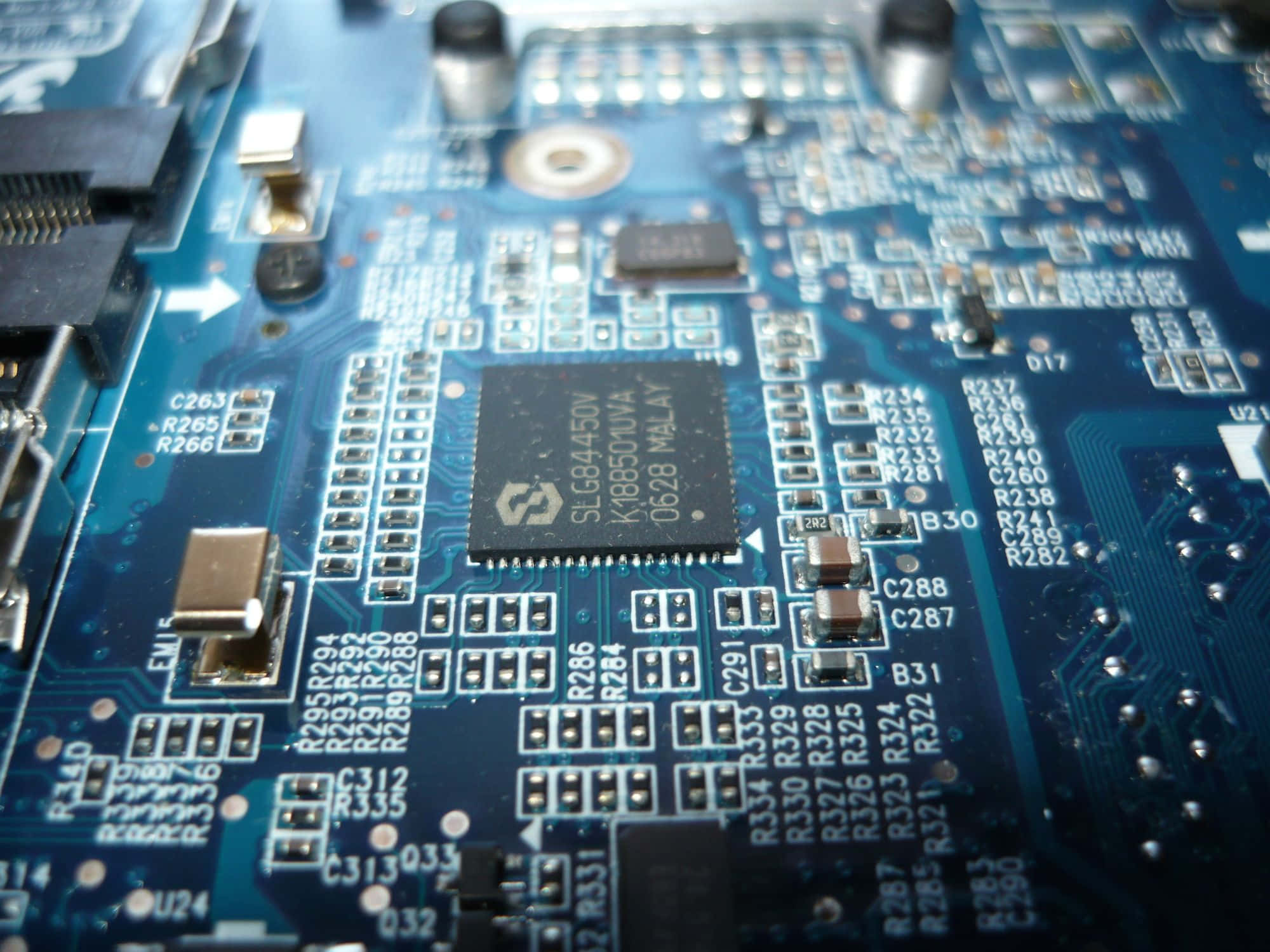 Electronics 桌布 壁紙 — 藍色電路板嘅特寫，上面有複雜嘅線路同標籤咗嘅電子零件，喺明亮嘅燈光下。
