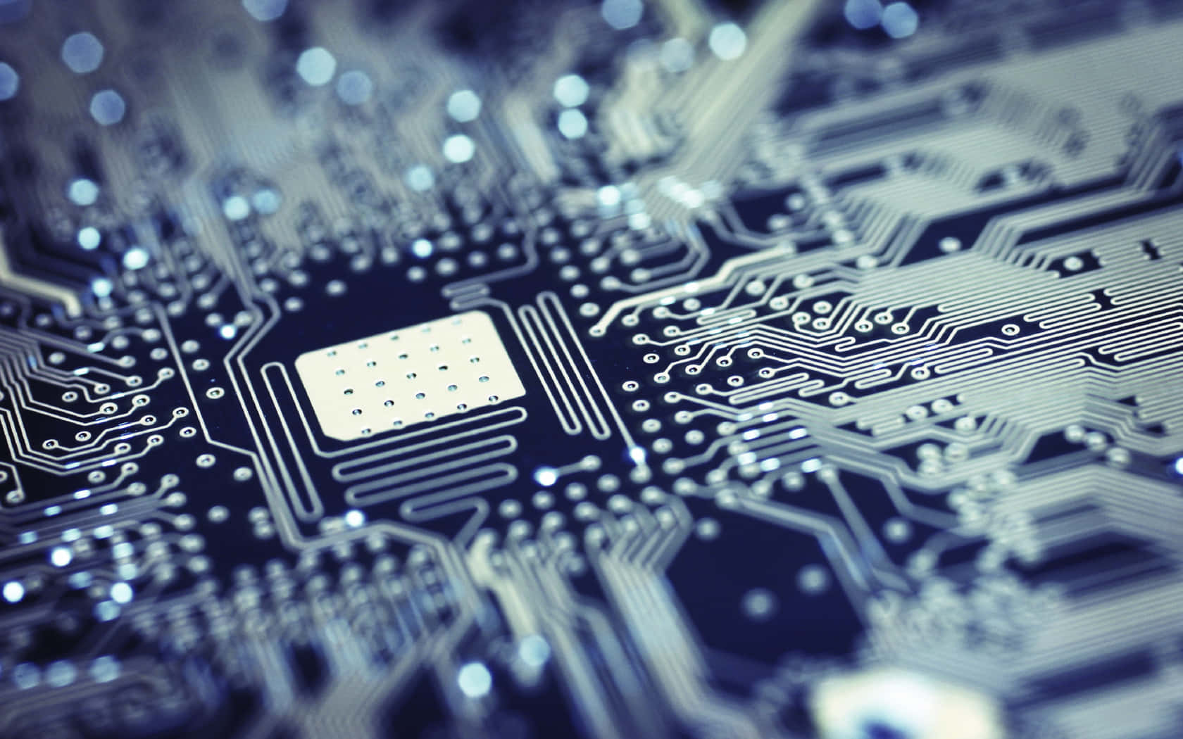 Electronics 桌布 壁紙 — 藍色電路板嘅特寫，帶有複雜嘅銀色路徑同一個中央晶片，喺淺景深下柔和發光。