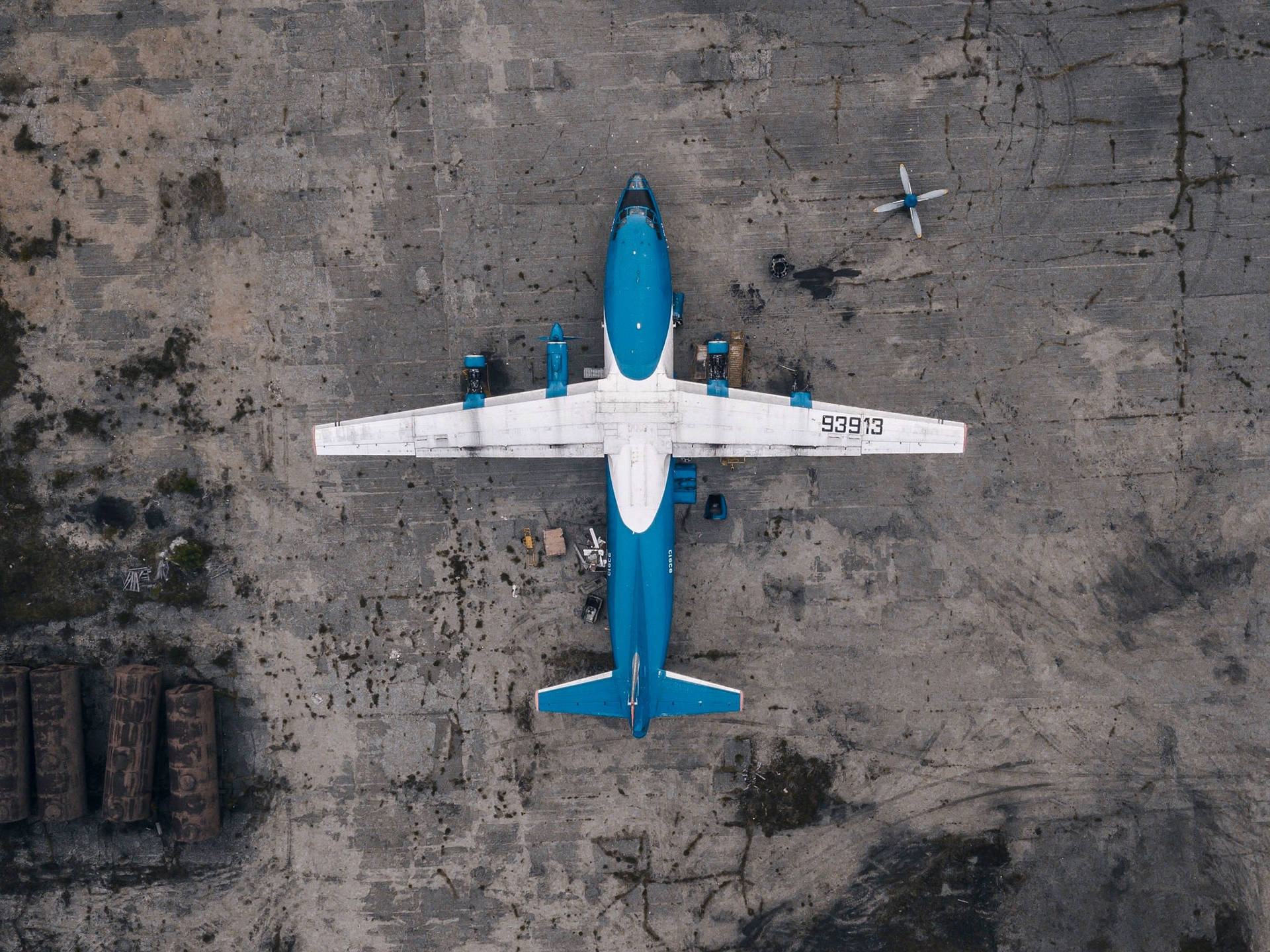 藍白相間的飛機停泊在龜裂的混凝土停機坪上，周圍散落著碎片。
