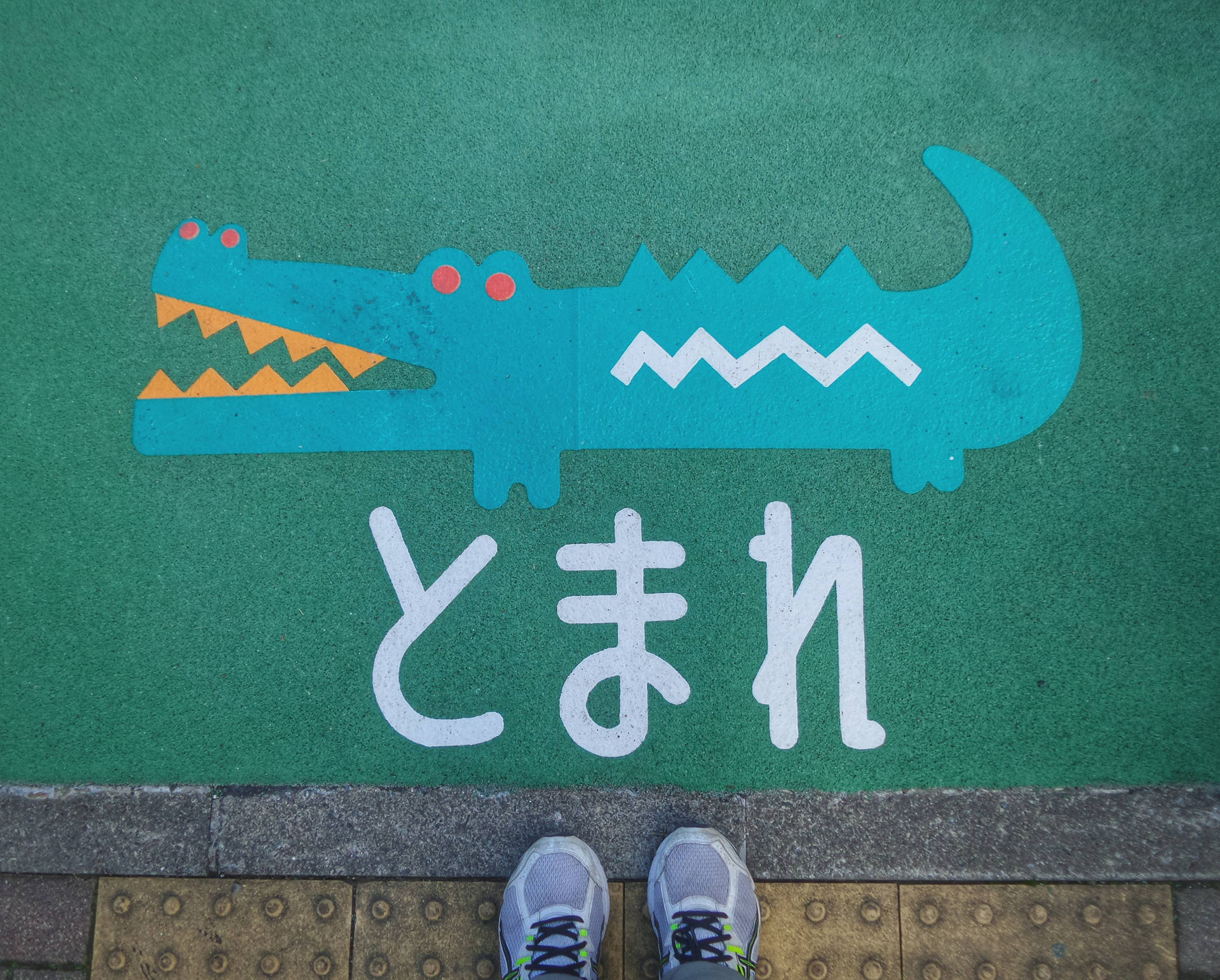 兒童運動鞋在鱷魚主題遊樂場標誌旁，帶有日文字元。