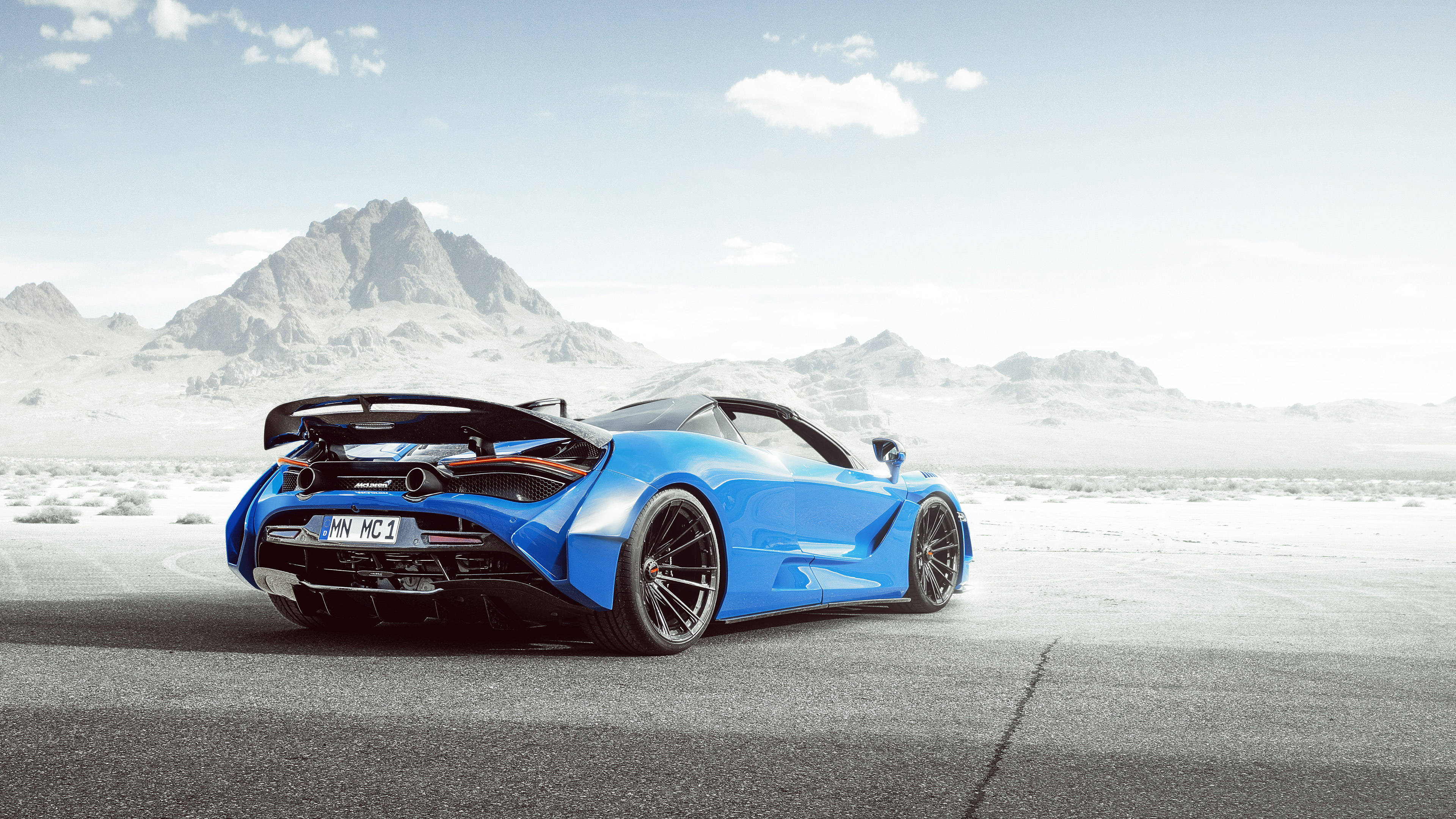 藍色麥拉倫720S 4K，背景為山脈 壁紙 — 一輛鮮藍色McLaren跑車停泊在沙漠公路上，背景是晴朗天空下的雪山。