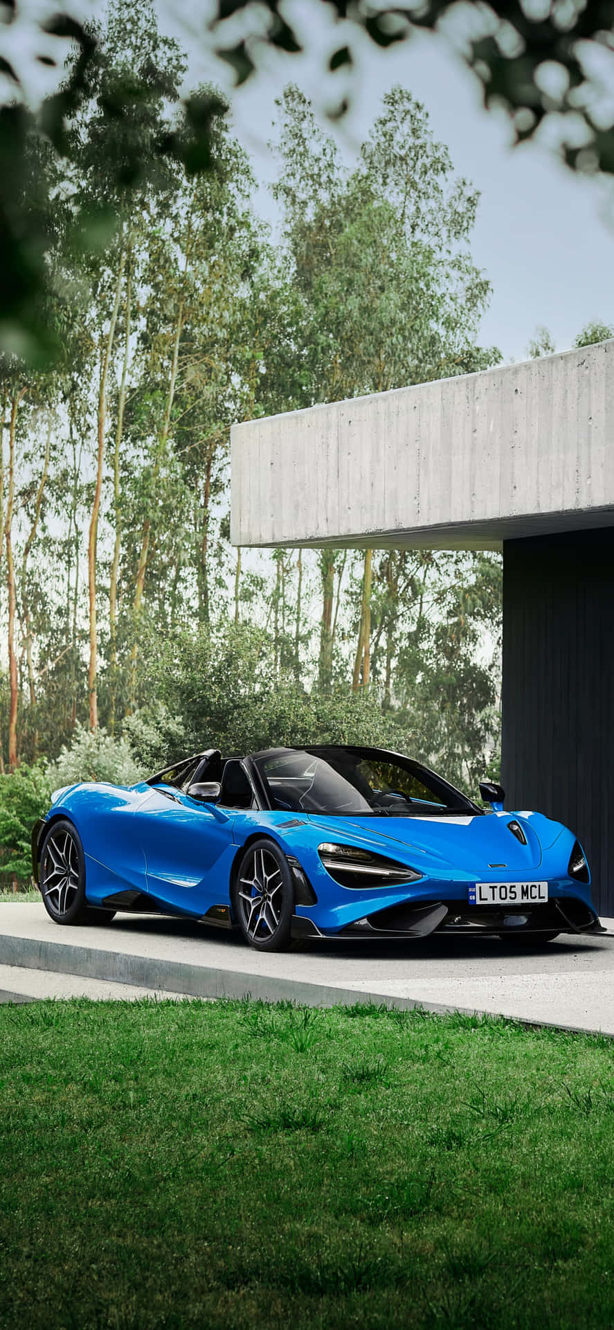 藍色McLaren 720S Spider停泊在現代房屋旁，周圍有樹木和草地。