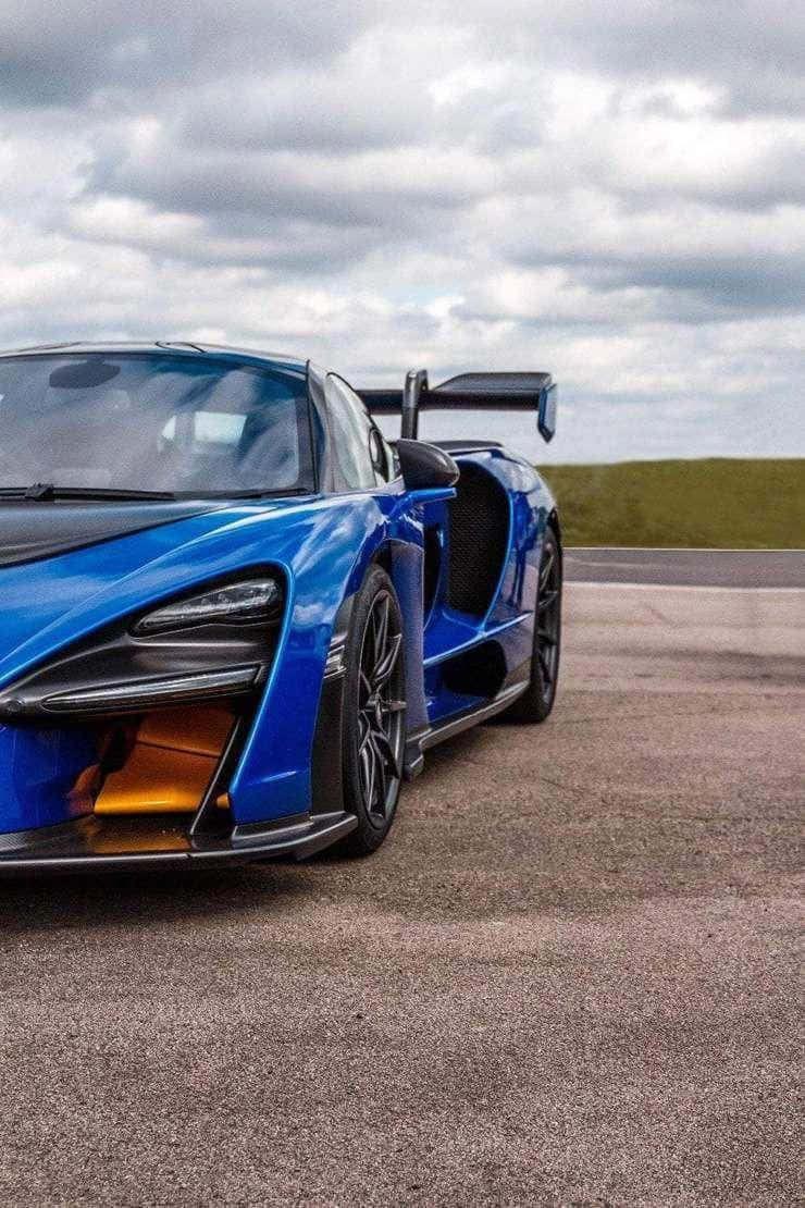 藍色McLaren Senna超級跑車在多雲天空下的瀝青賽道上