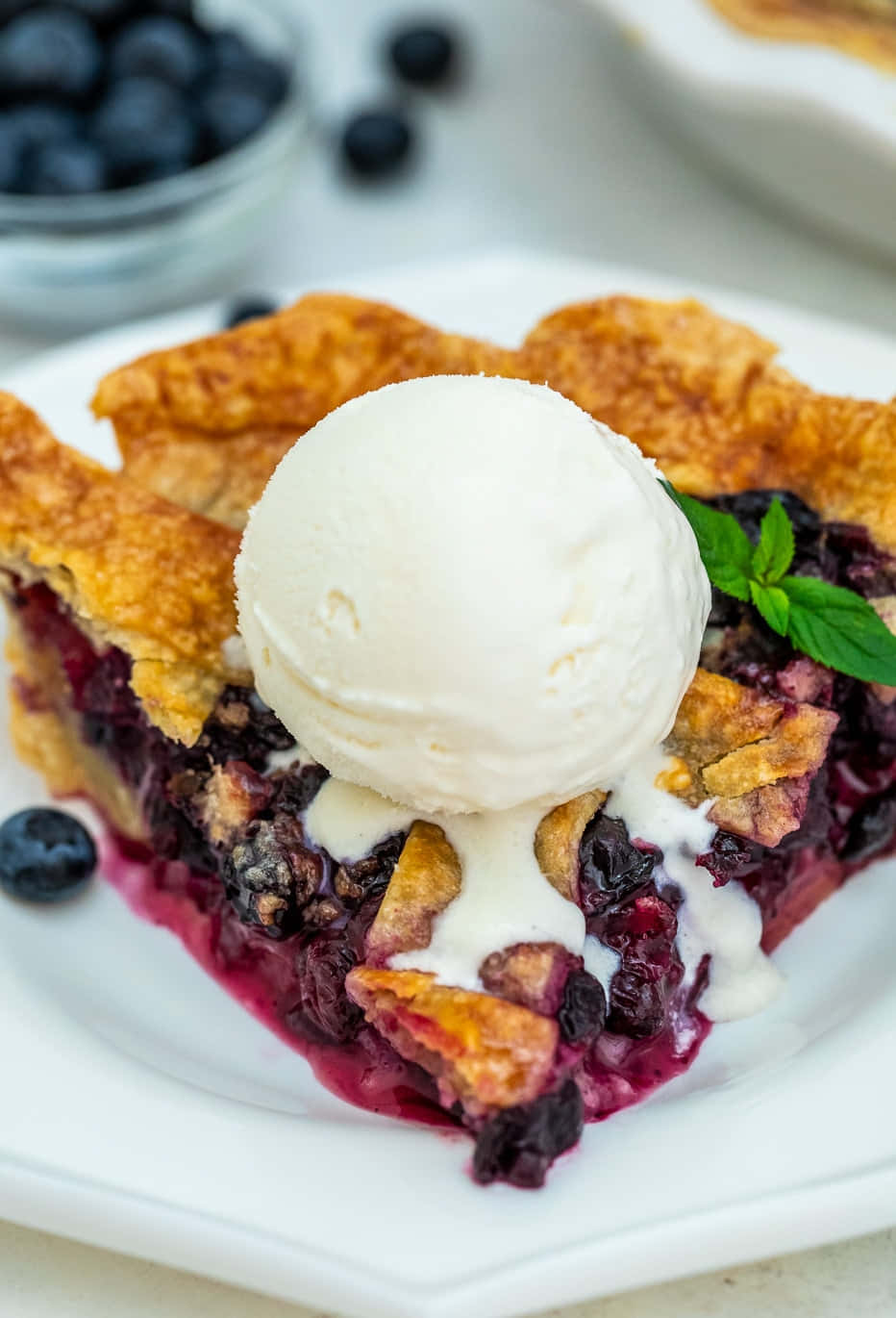Blueberry Pie 桌布 壁紙 — 藍莓批一片的特寫，金黃色的批皮上配有融化的雲呢拿雪糕和新鮮薄荷。