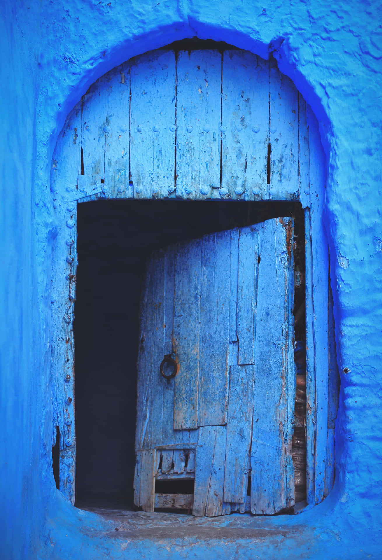 一扇質樸的藍色木門在藍色洗石拱門中微微敞開。