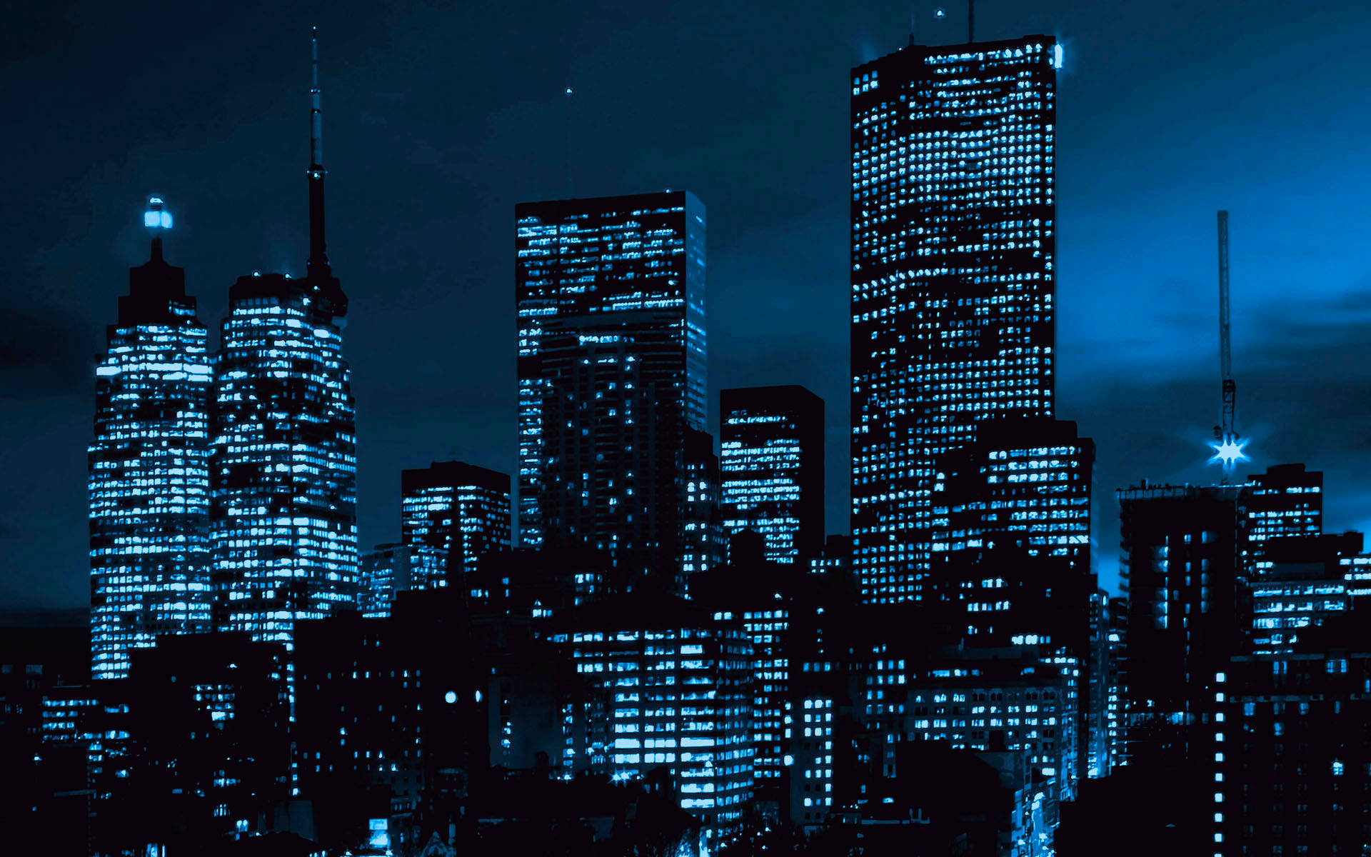 藍色燈光的摩天大樓在黑暗的天空下主導了夜景。