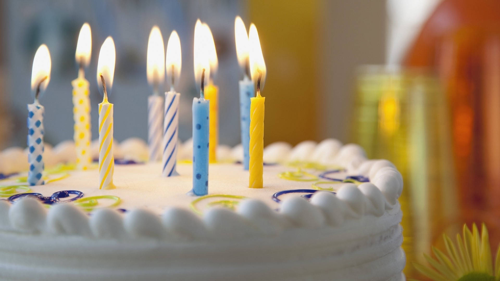 一個生日蛋糕，帶有藍色、黃色和條紋圖案的點燃蠟燭。 — 蠟燭 GIF 壁紙
