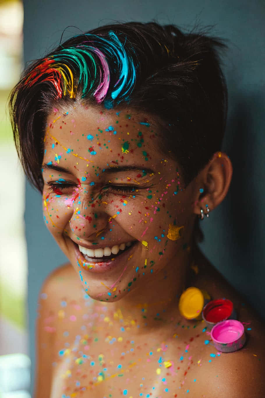 藝術可愛LGBT微笑肖像 壁紙 — 一個快樂的人臉上和頭髮上有鮮豔的油漆飛濺，笑著拿著打開的油漆罐。