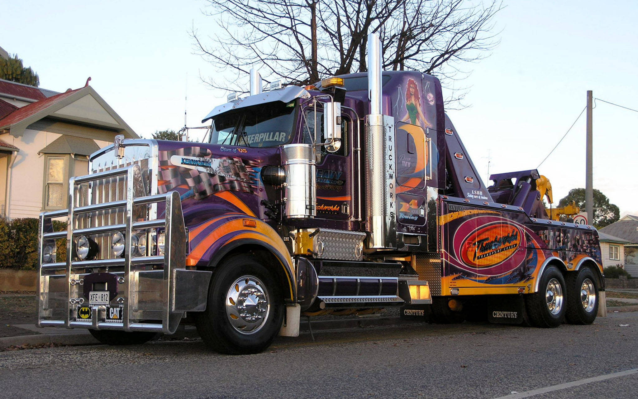 藝術風格Kenworth W900 壁紙 — 一輛帶有鍍鉻裝飾的鮮豔紫色和橙色定制拖車，在黎明時分停放在住宅街道上。