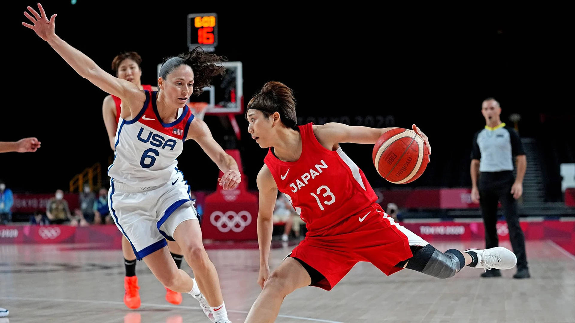 日本籃球運動員在奧運比賽中運球越過美國防守球員。