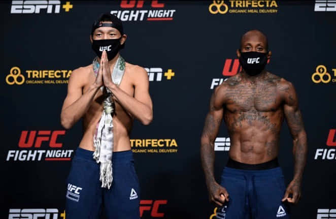 兩名UFC拳手在過磅活動中戴著口罩和藍色短褲。