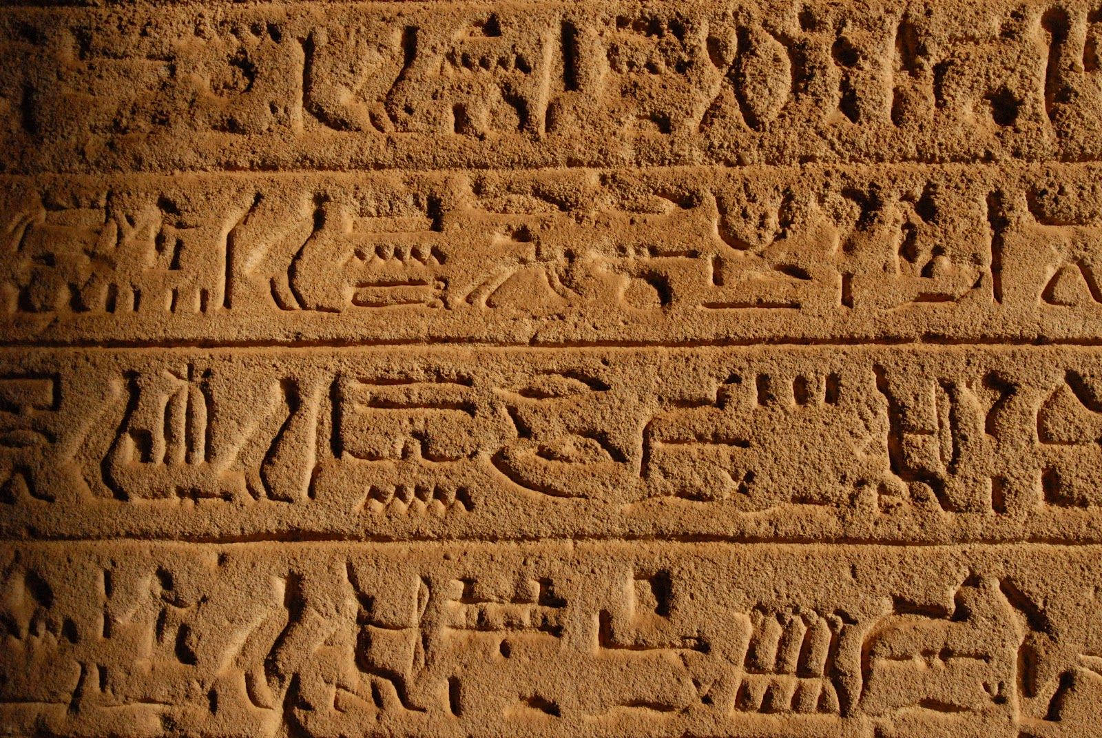 蘇丹古代密碼石板 壁紙 — 特寫鏡頭：溫暖金色光線下，刻在紋理砂岩上的古埃及象形文字。