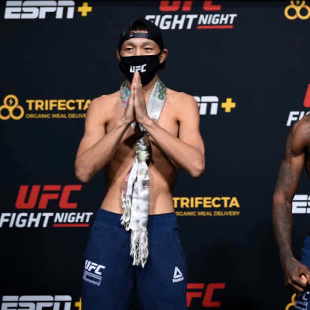 UFC拳手穿著藍色短褲和口罩在稱重時雙手合十。