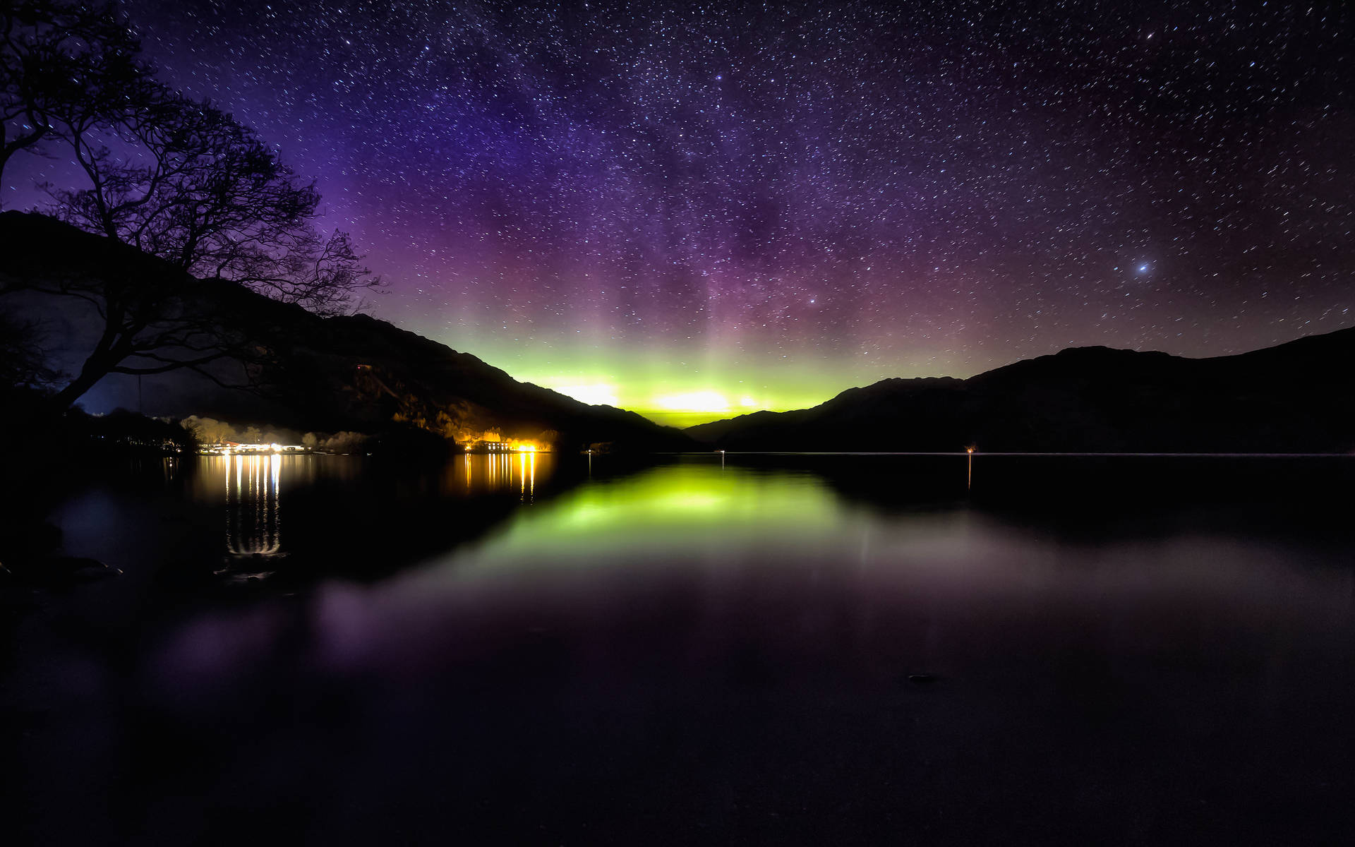 北極光在夜晚的星空湖上閃耀，山巒剪影。