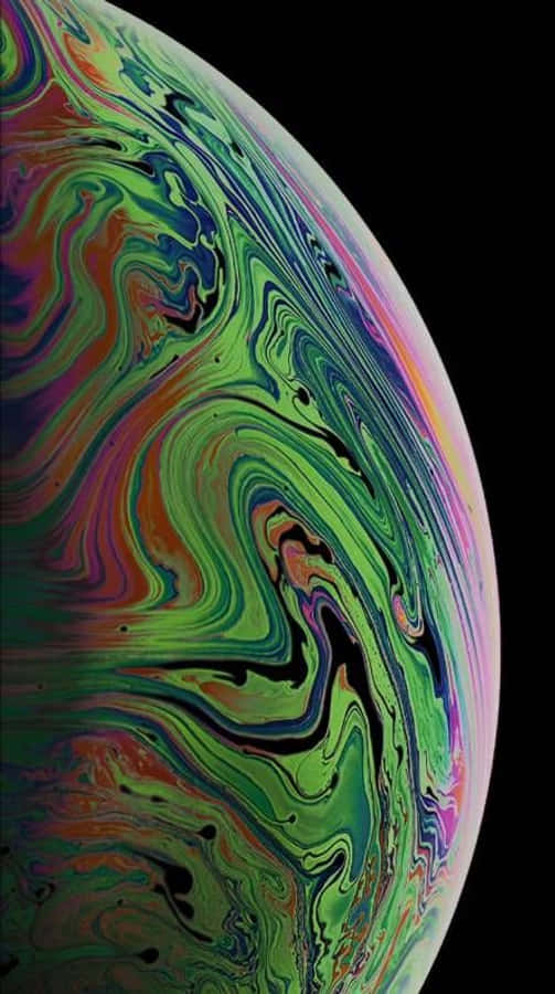 蘋果 iPhone X 的絕美 OLED 屏幕 壁紙 — 一個充滿活力的旋轉肥皂泡，帶有虹彩的綠色、紫色和粉紅色，背景為黑色。