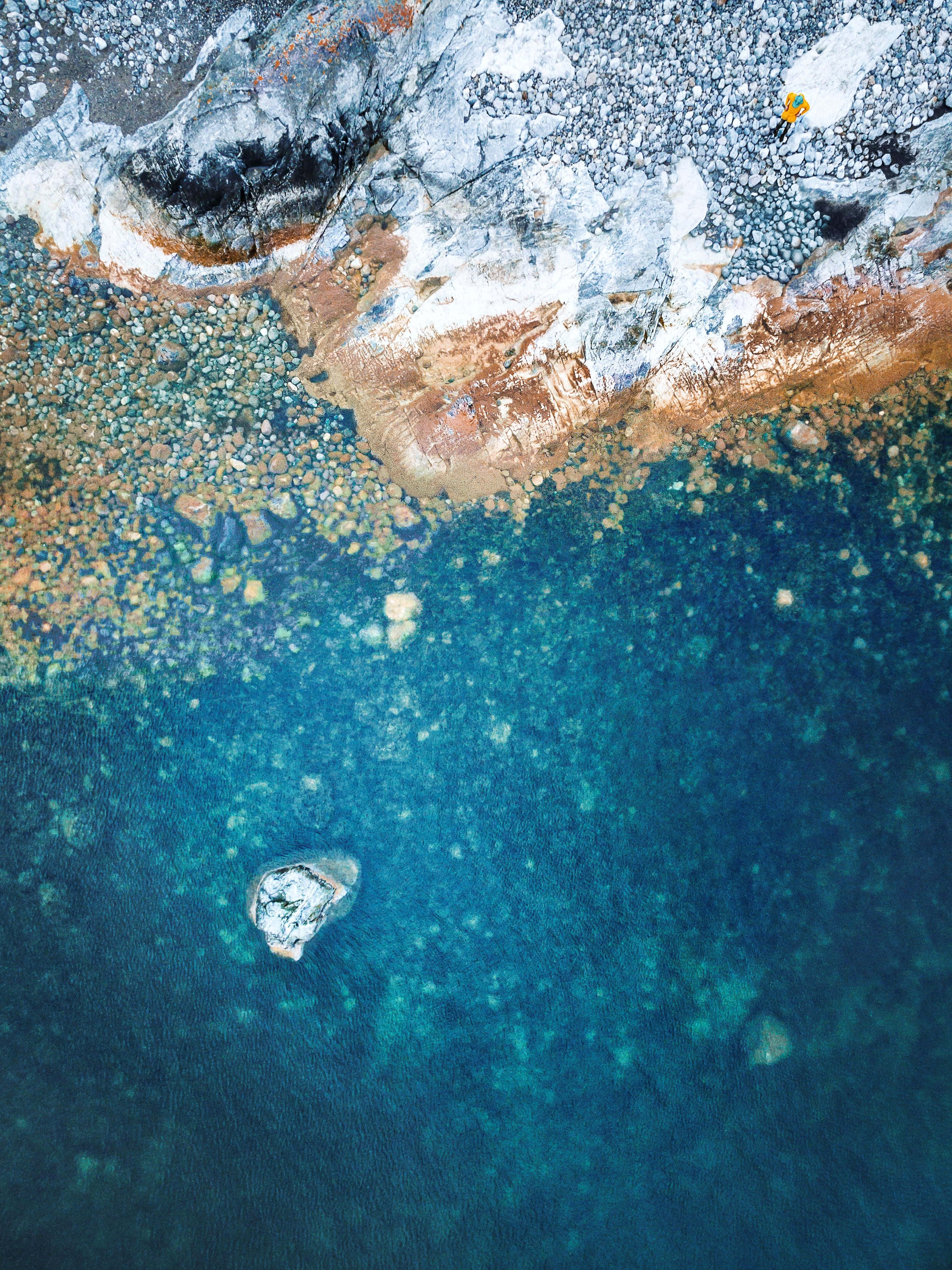 蘋果iPad搭配原廠壁紙 壁紙 — 岩石海岸線的鳥瞰圖，碧綠海水，一名獨自游泳者靠近一個小島。