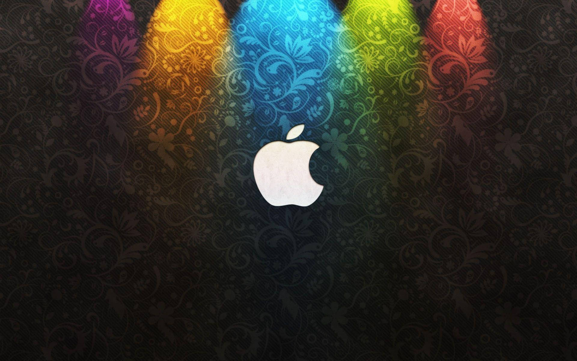 Apple標誌在深色花卉背景上被彩色聚光燈照亮。