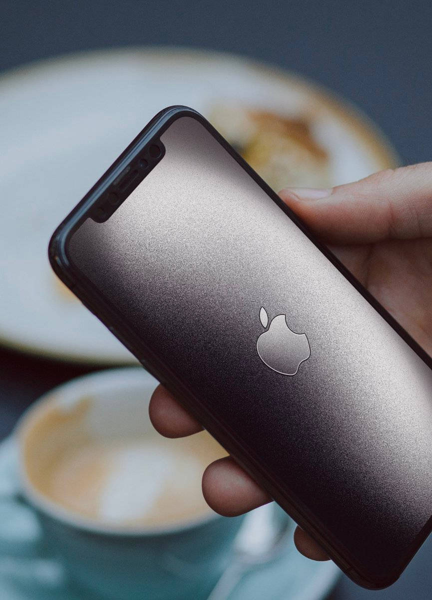 手在咖啡和糕點附近拿著深灰色iPhone。
