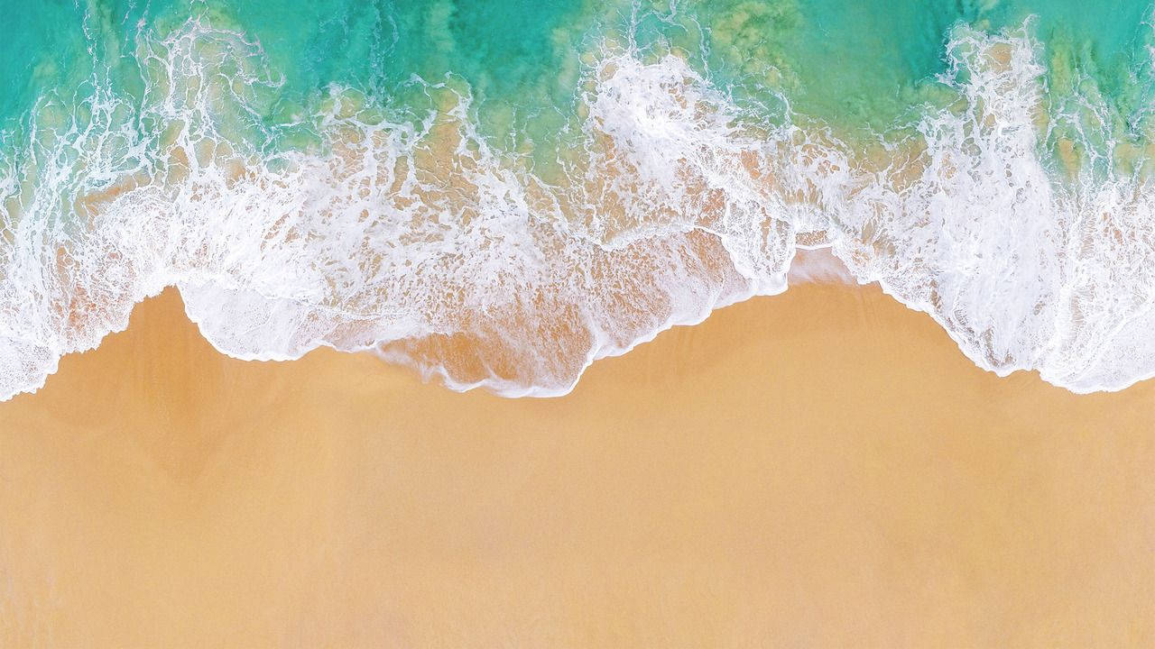 碧綠色的海浪從上方輕輕滾上金色沙灘。