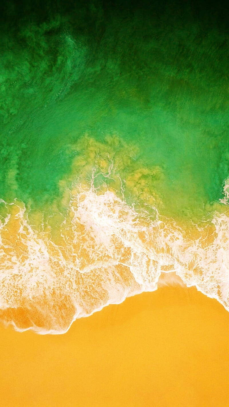 翠綠的海浪在金色沙灘上破碎，泛起白色泡沫。