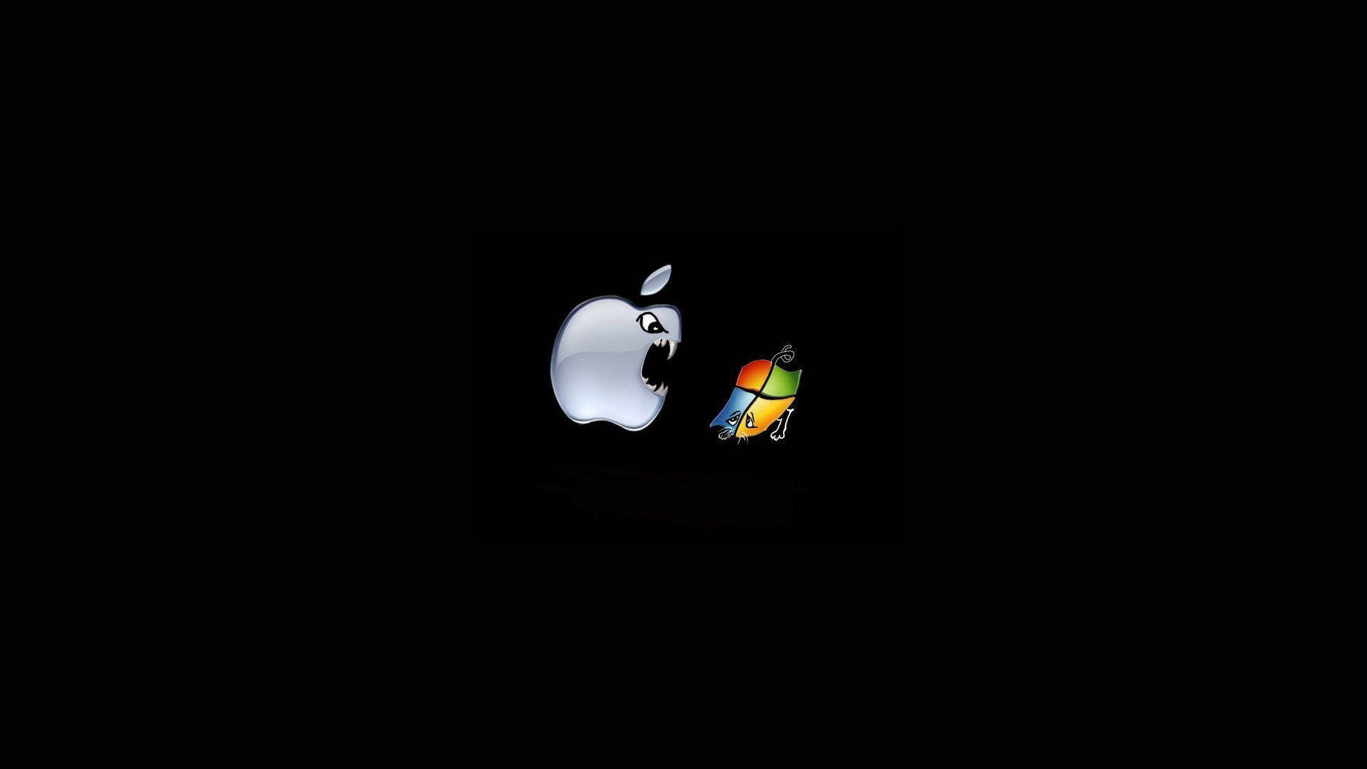 蘋果與 Windows 標誌對打搞笑筆電 壁紙 — 一個帶有露齒的威脅性Apple標誌，在黑色背景上與一個細小色彩繽紛的Mac OS X標誌對峙。