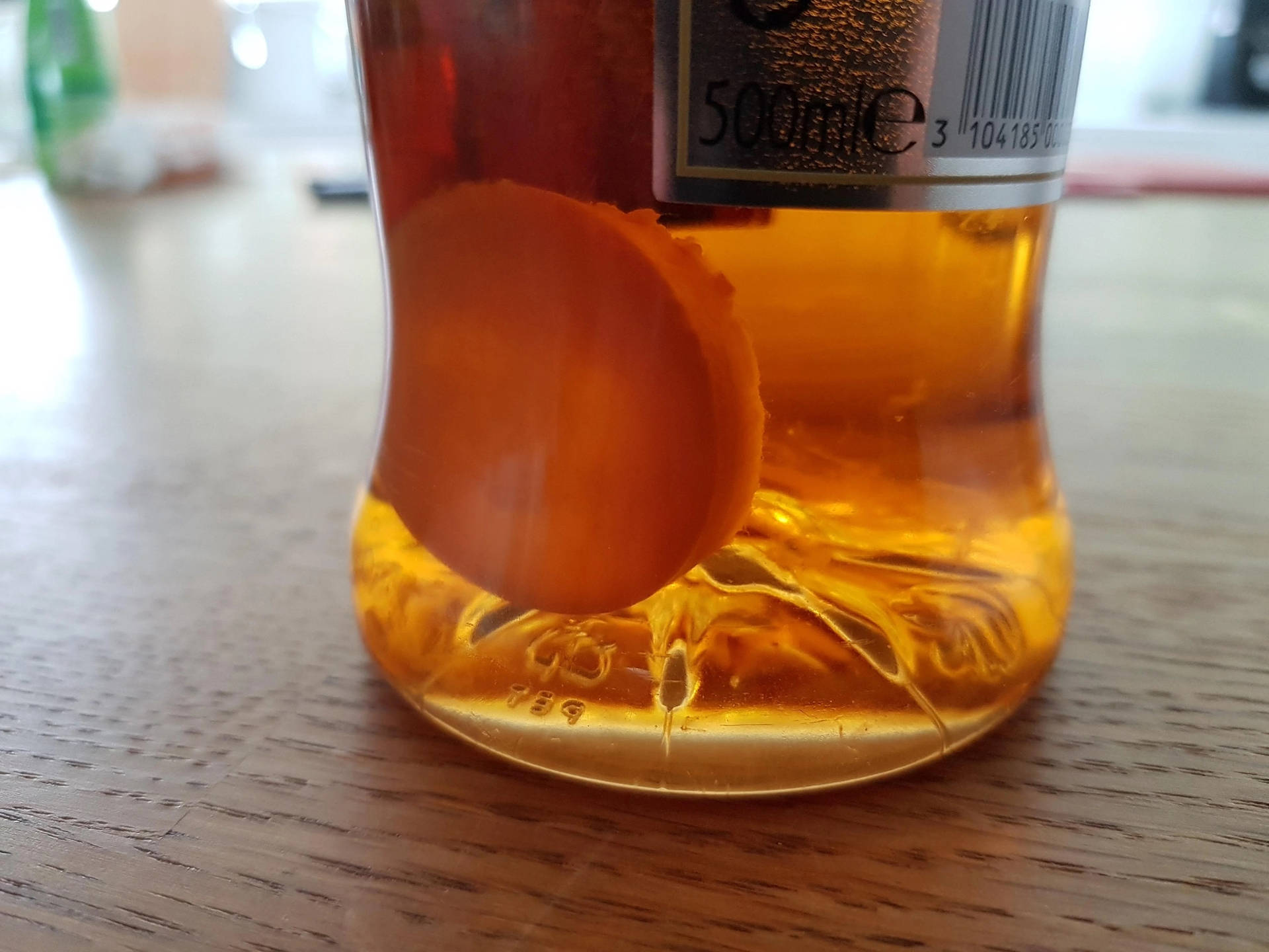 木質表面上琥珀色液體瓶，內有漂浮的橙片。