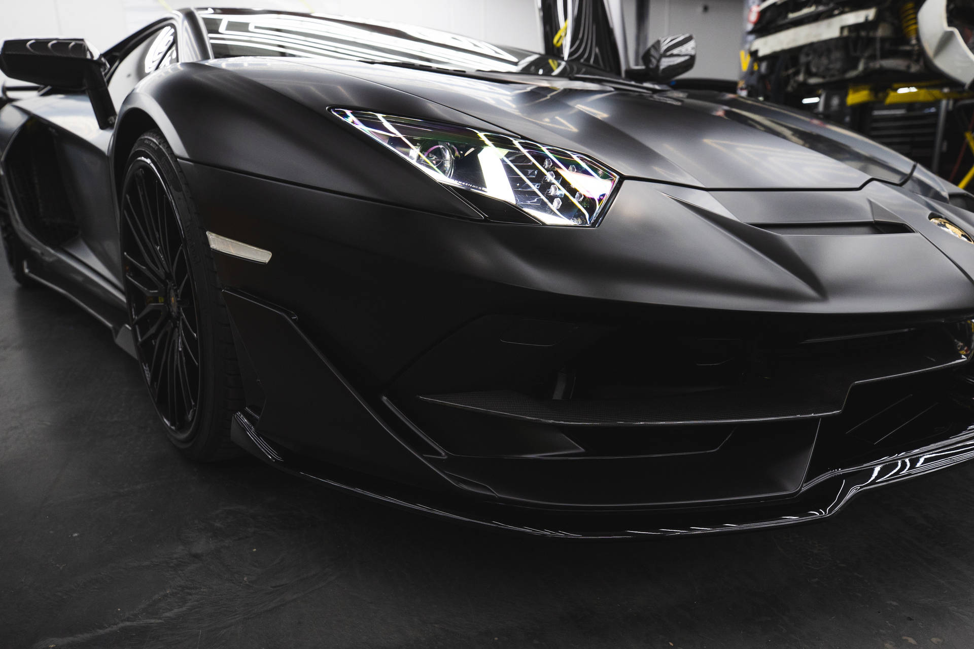 啞光黑色林寶堅尼 Aventador 在車庫中，車頭燈閃爍。