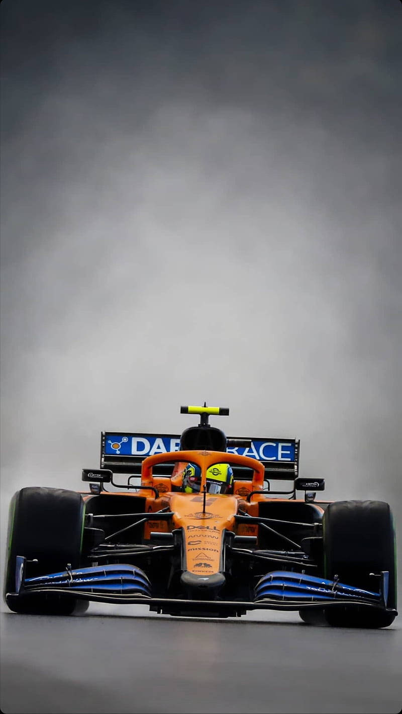 橙色和藍色的 Formula 1 賽車在賽道上，背景有煙霧。