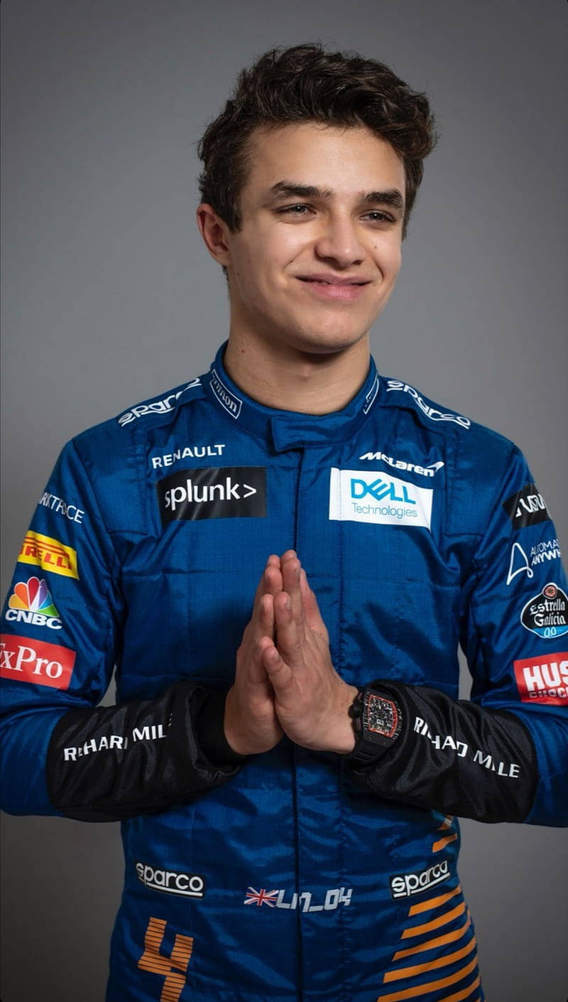 年輕男性賽車手身穿藍色McLaren賽車服，雙手合十微笑。