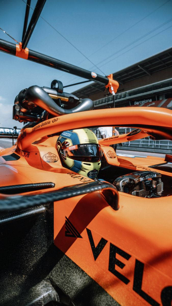 日落時分在巴塞隆拿賽道上駕駛橙色麥拿侖賽車的F1車手。