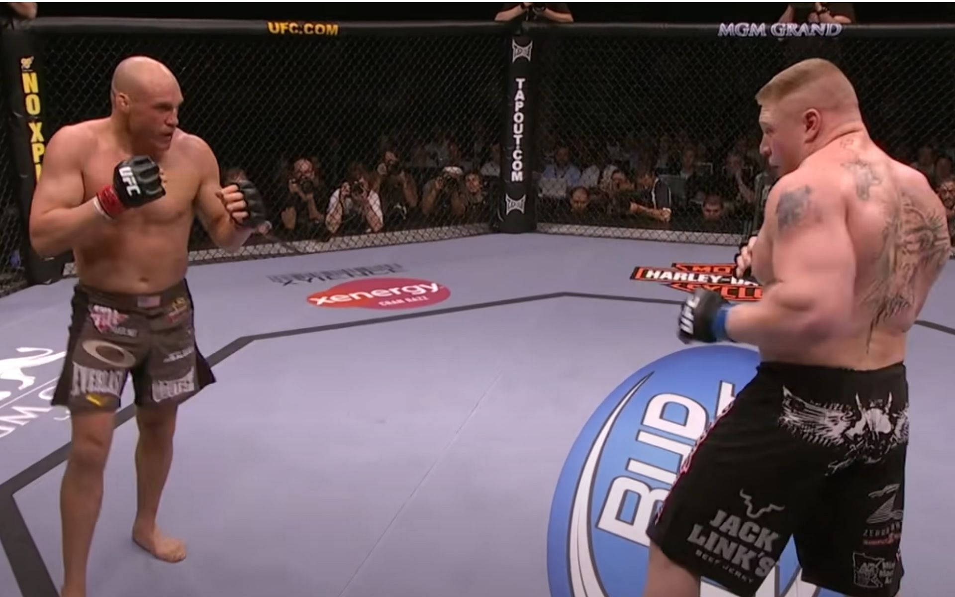 蘭迪·庫圖爾對決布洛克·萊斯納 壁紙 — 兩名肌肉發達的MMA拳手在UFC八角籠中對峙，觀眾和贊助商標誌清晰可見。