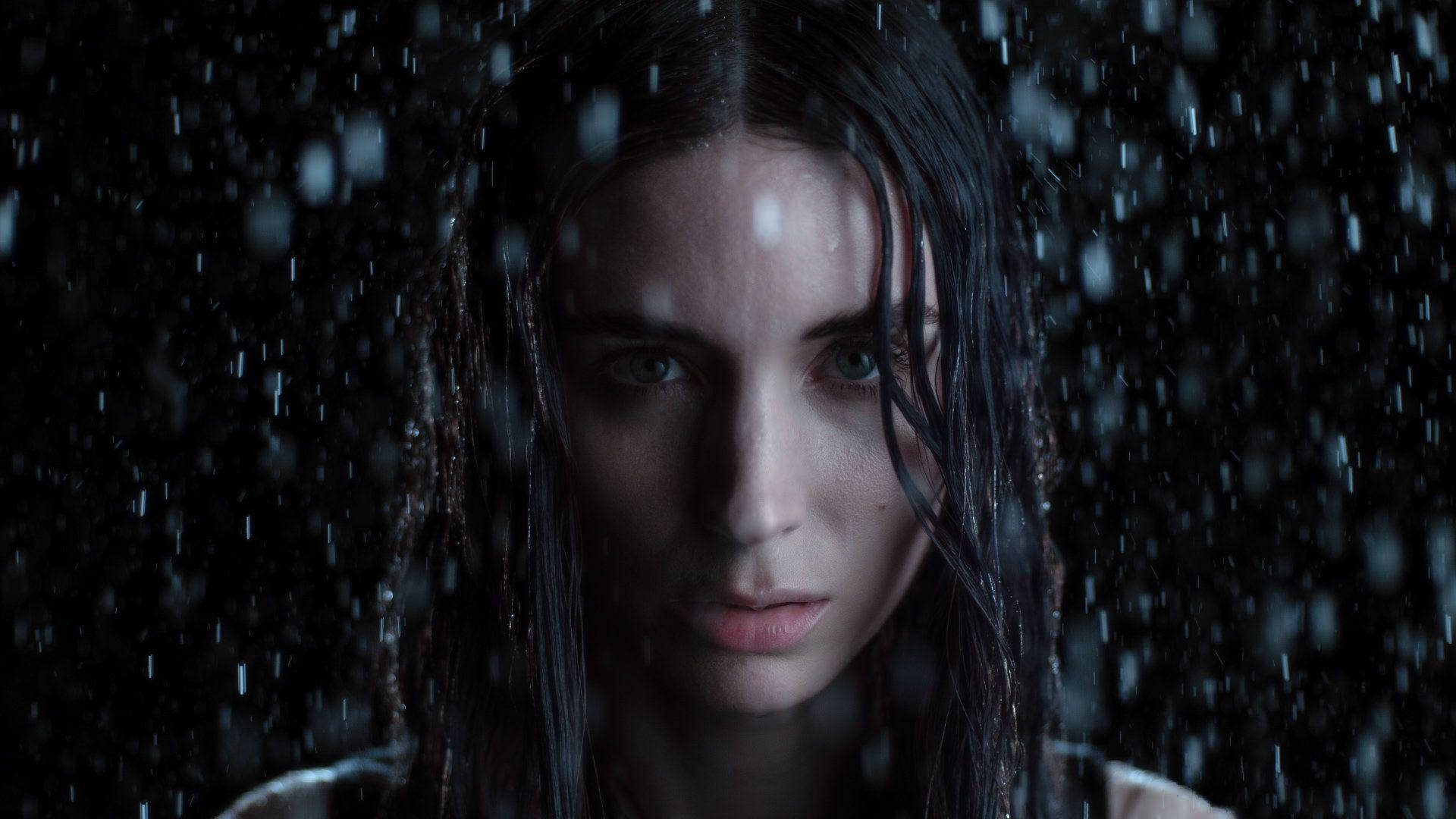 濕髮女人在黑暗環境中透過雨水凝視