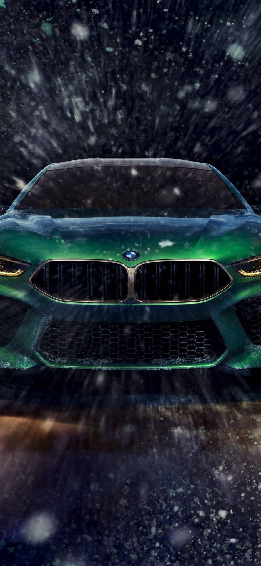 綠色BMW跑車在夜間大雪中行駛，車頭燈閃閃發光。