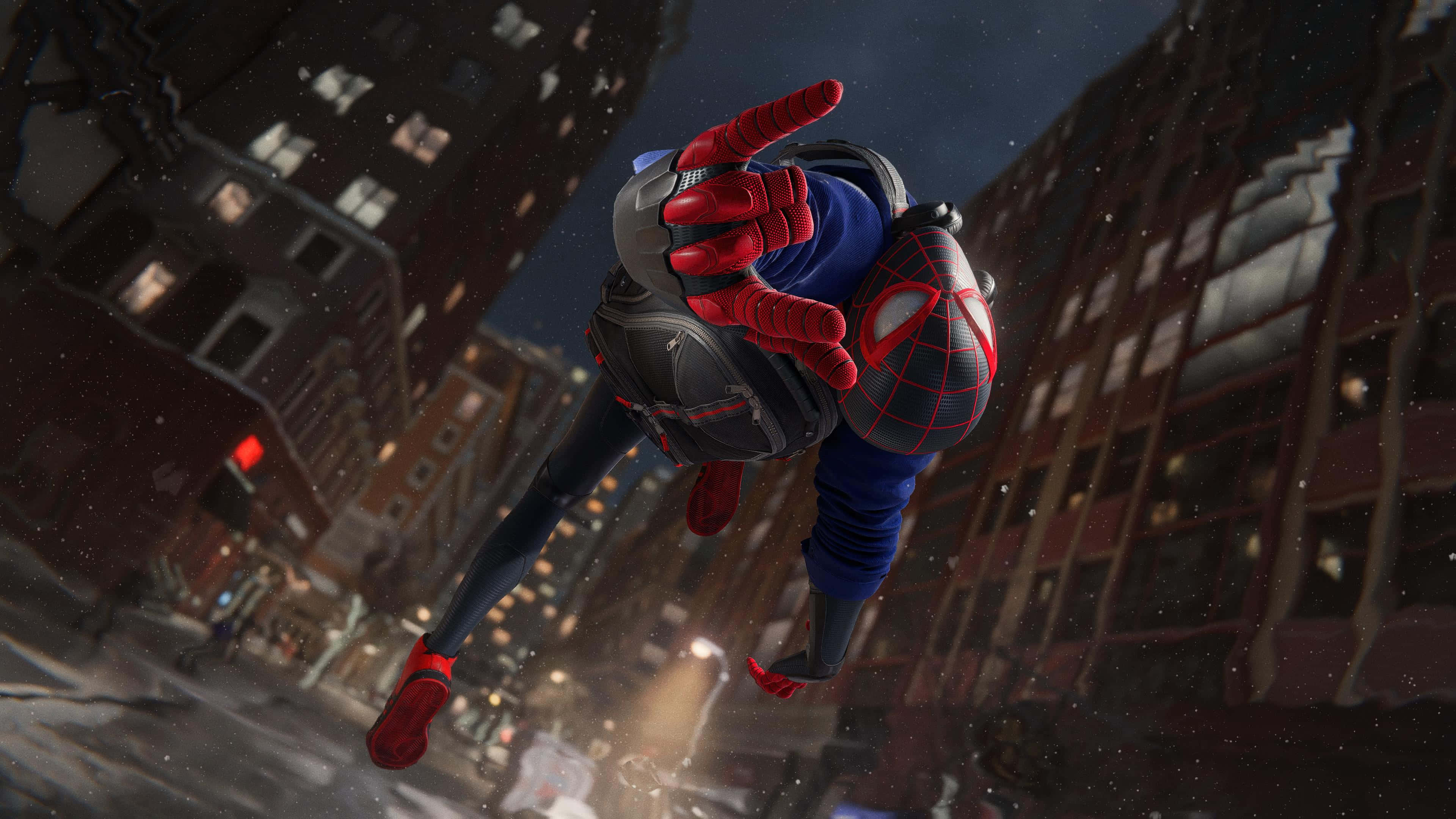Web-slinging 桌布 壁紙 — 蜘蛛俠在夜晚穿越白雪覆蓋的城市景觀，下方是高聳的建築物，周圍飄落著雪花。