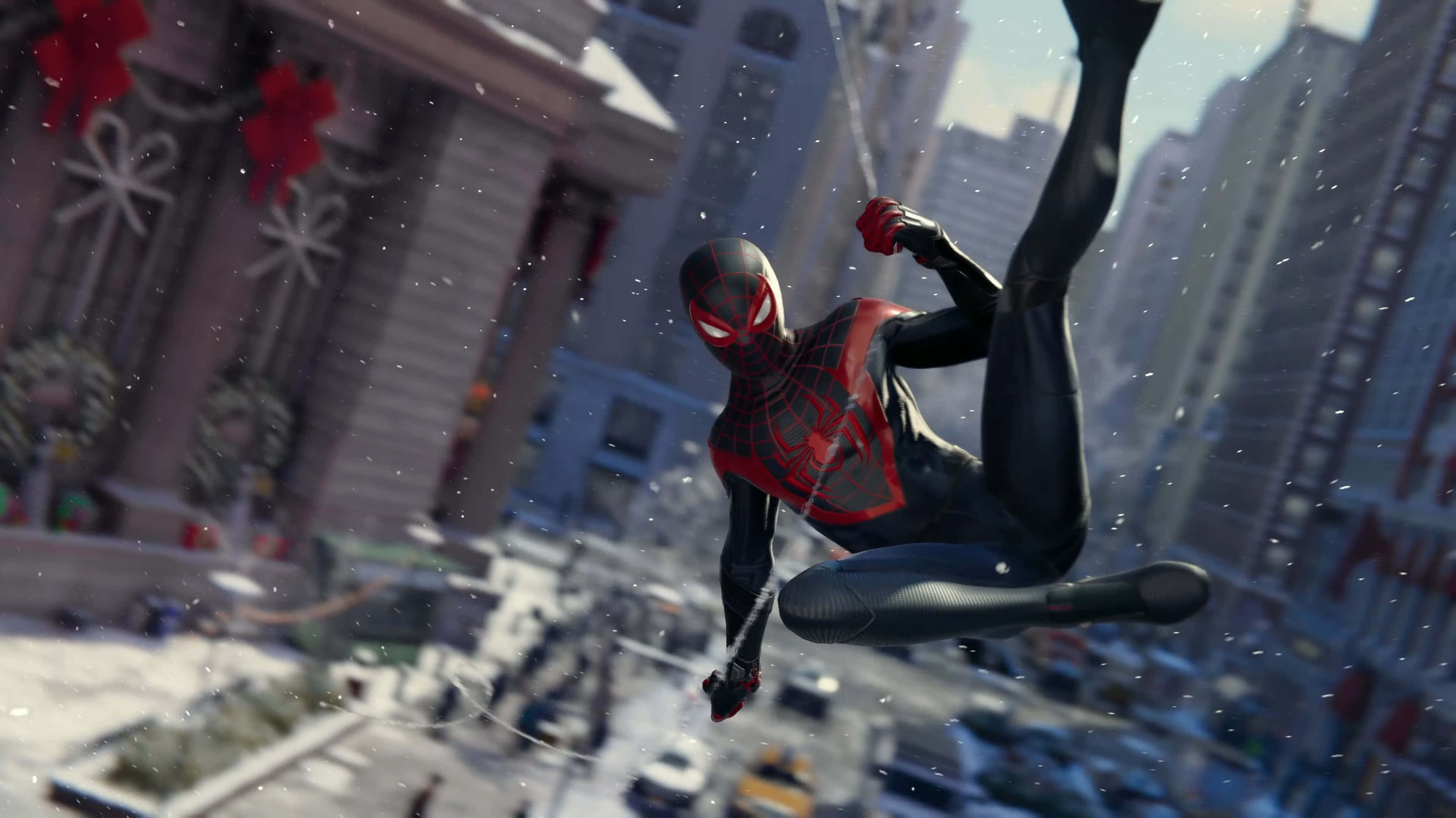 Miles Morales 動漫 桌布 壁紙 — 蜘蛛俠在雪景城市中擺盪，周圍有節日紅蝴蝶結和飄落的雪花。