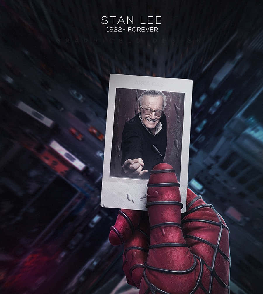 Stan Lee Tribute 桌布 壁紙 — 蜘蛛俠的手拿著一張史丹·李微笑的寶麗來照片，背景是夜晚模糊的城市景觀。